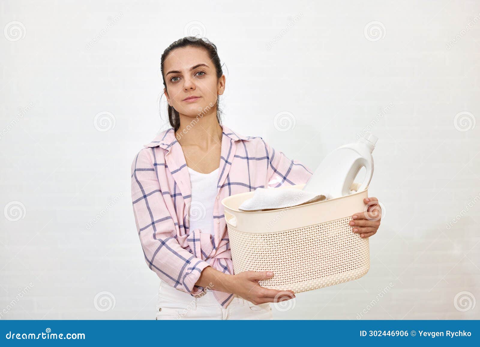 Mujer sonriente que sostiene la cesta y que cuelga la ropa con las