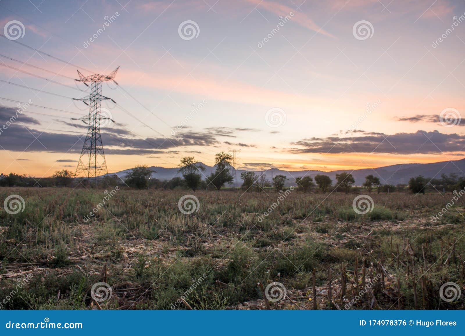 electrical tower and cables in a field at sunset