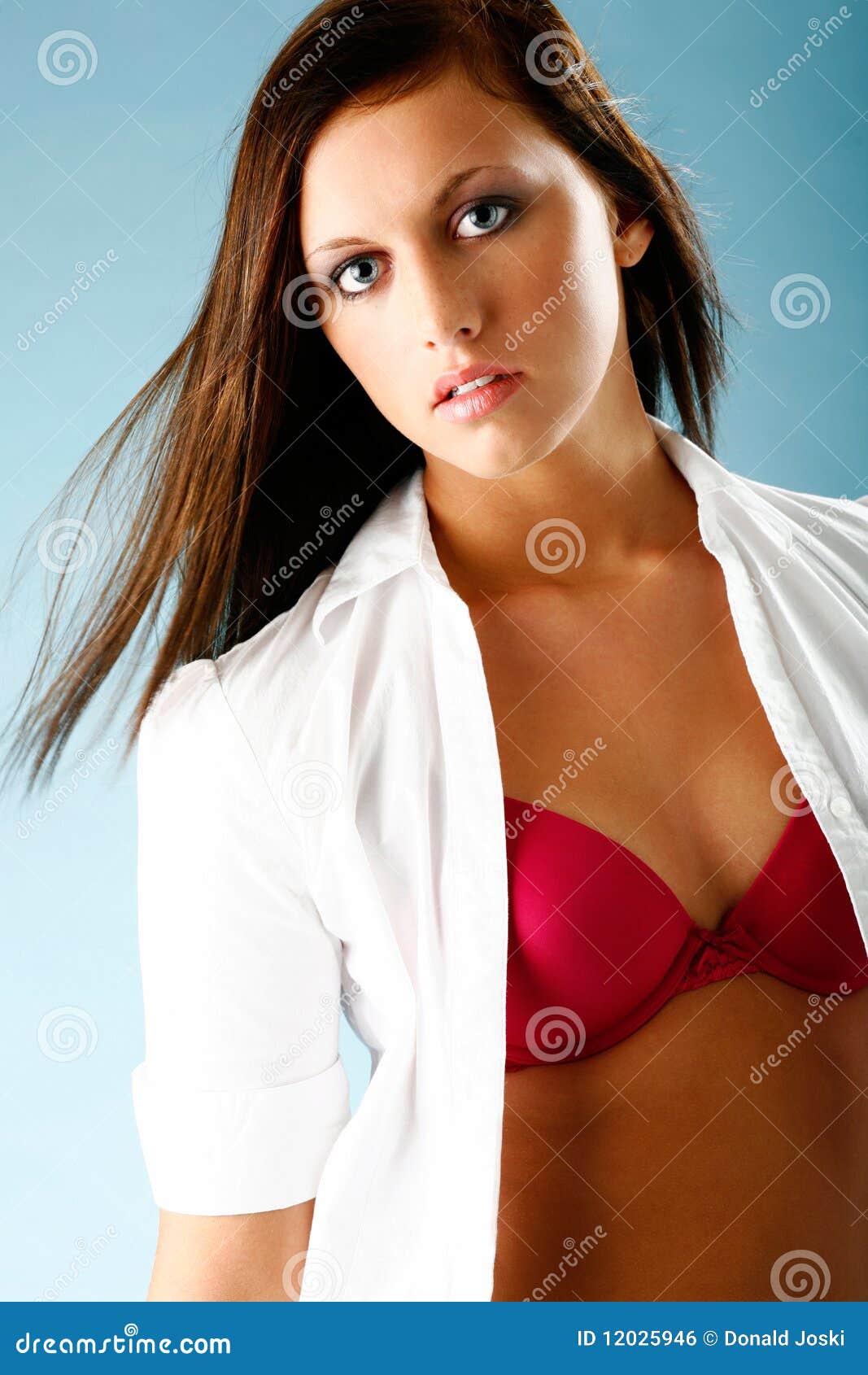 Photo about Young woman poses wearing white button shirt in studio. 