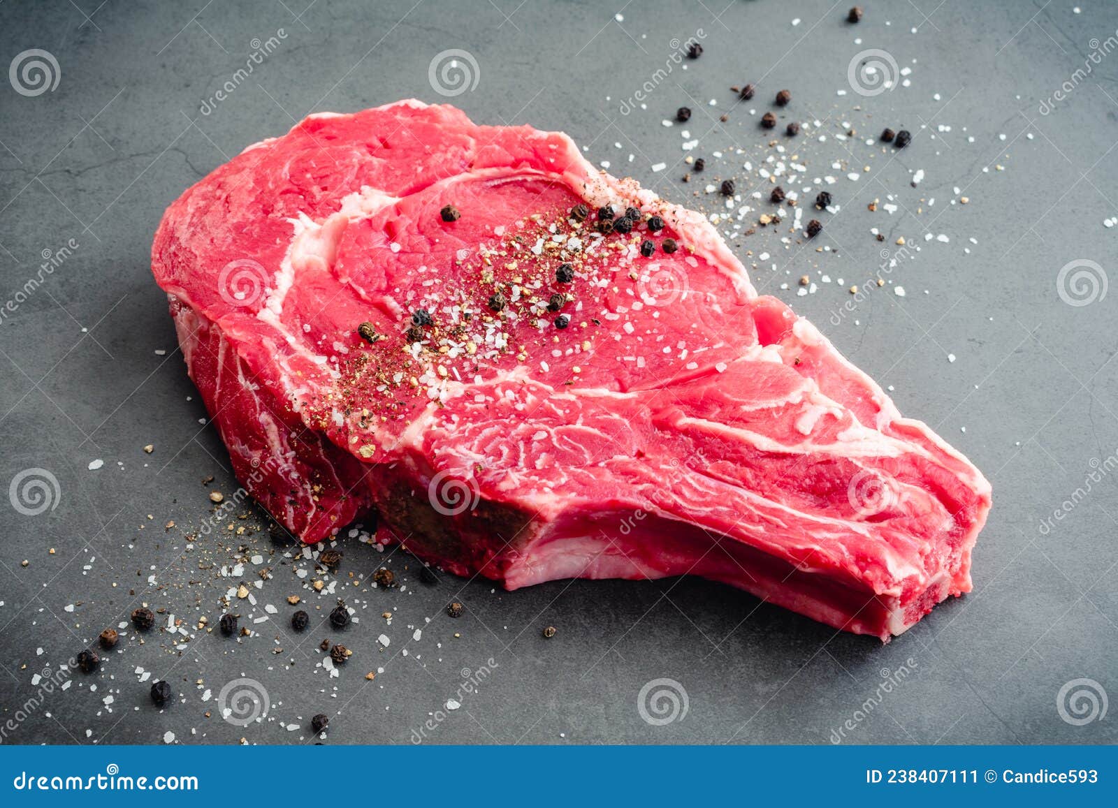 raw bone-in ribeye steak seasoned with kosher salt and black pepper
