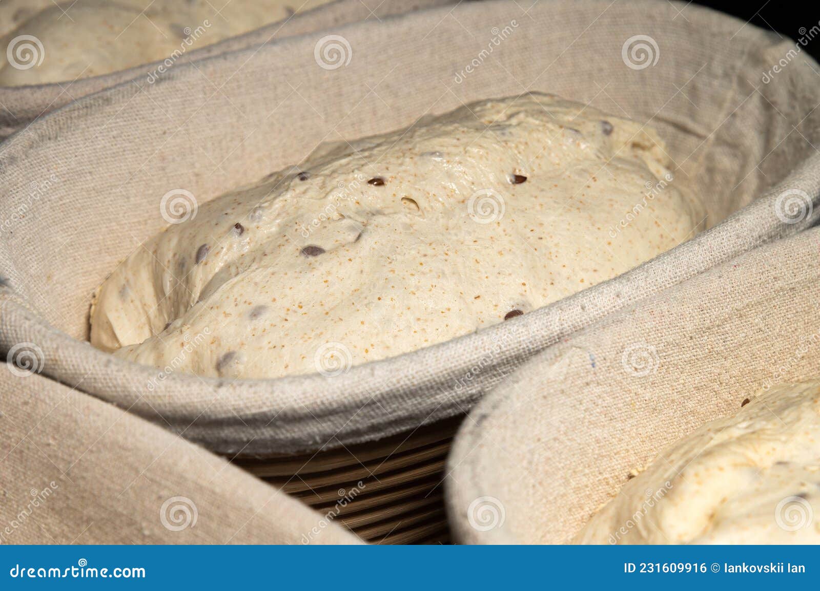 Uncooked Bread Dough with Sprinkles in Wooden Wicker Forms Covered with