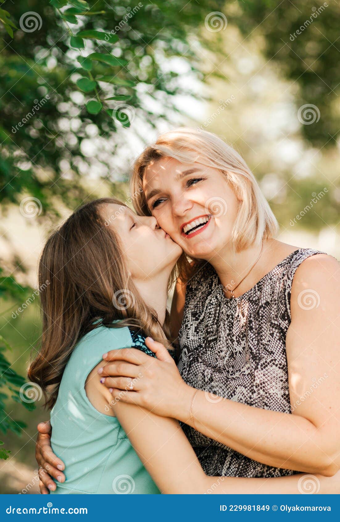 Une Adolescente Embrasse Sa Mère Sur La Joue Dans La Nature En été