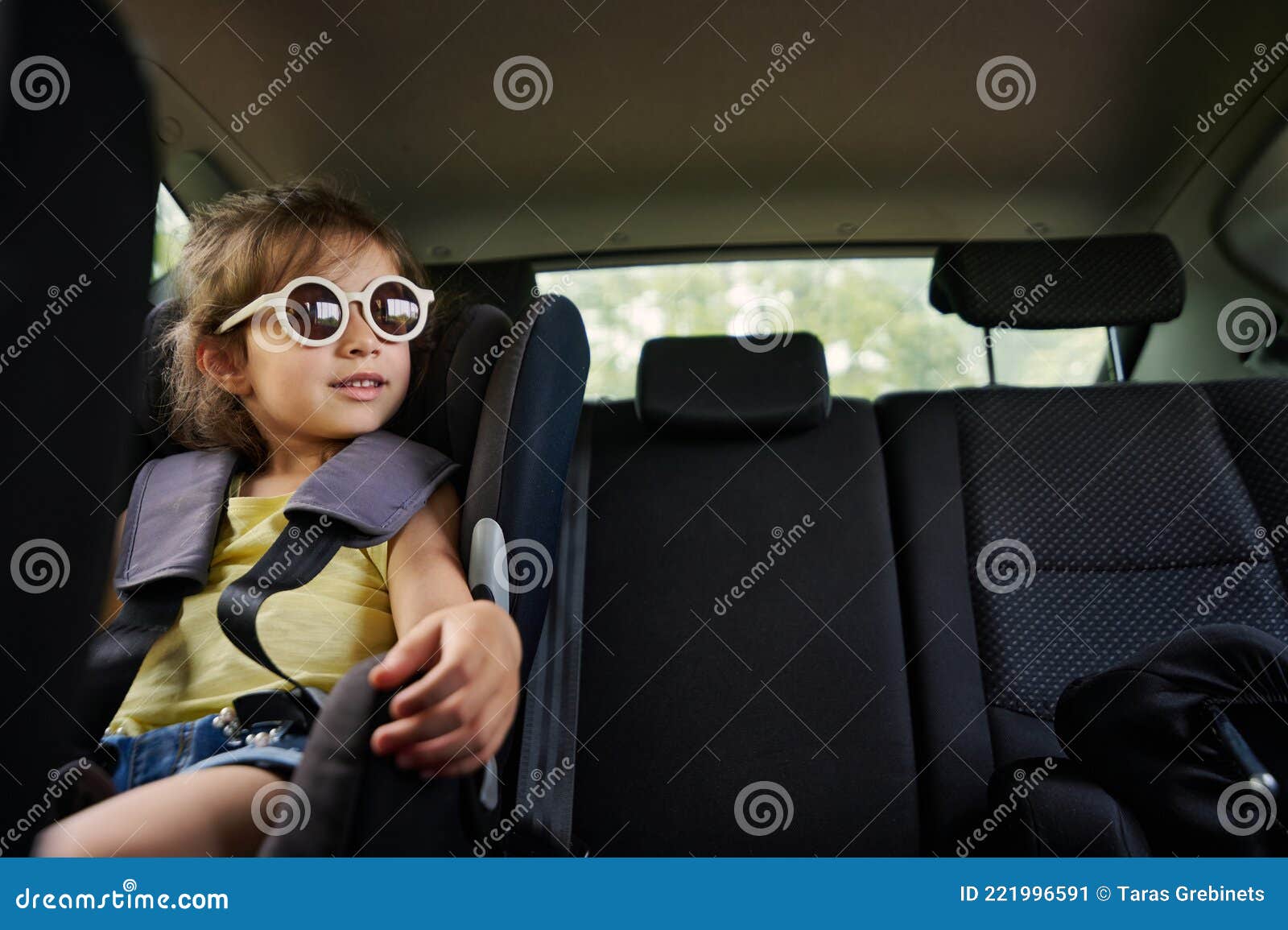 Une Belle Fille En Lunettes De Soleil Se Trouve Dans Un Siège De Voiture  Enfant Dans La Voiture Et Regarde Par La Fenêtre. Voyage Image stock -  Image du piloter, confortable: 221996591