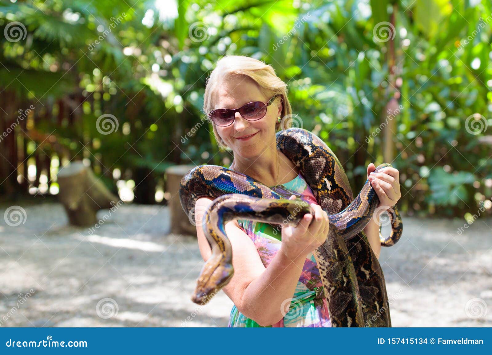 Ребенок держит змею. Женскую рептилию, держащую смешанного ребёнка.. Женщина смотрит на змею в зоопарке.