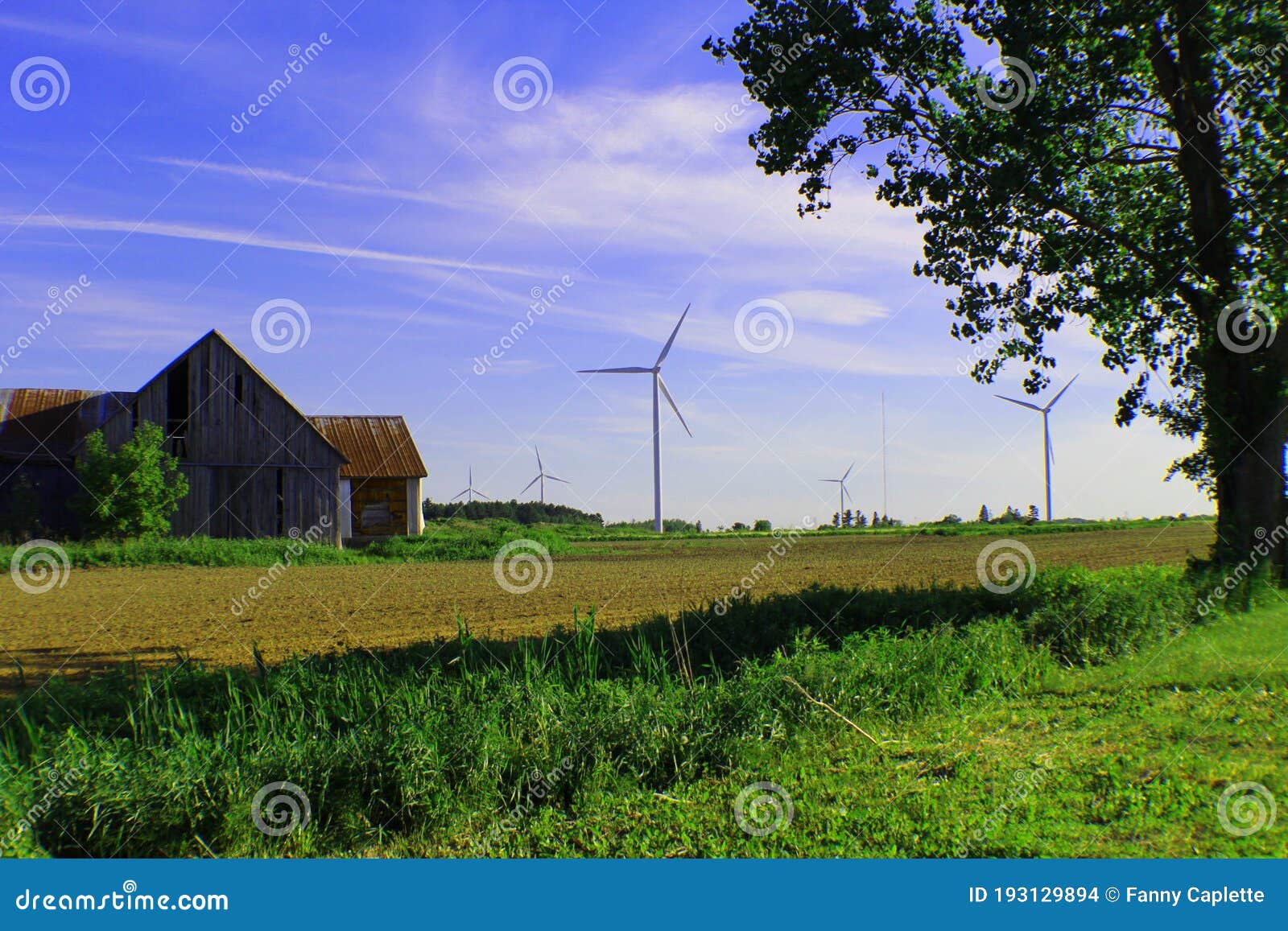 une vieille grange et des ÃÂ©oliennes dans un ciel bleu