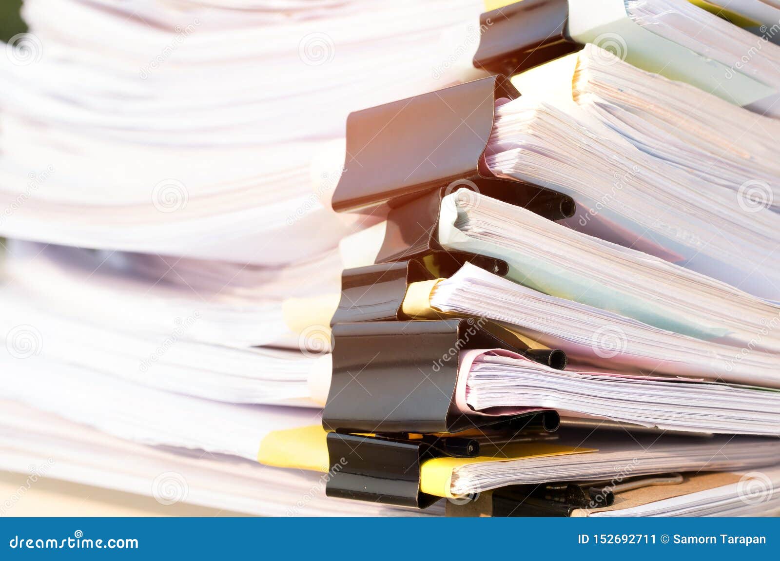 unfinished documents stacks of paper files on office desk for report papers, piles of unfinish sheet achieves with black clips.