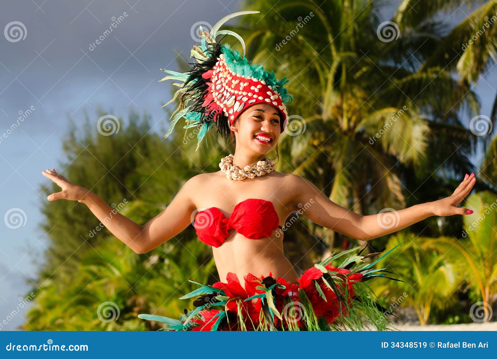 Ung Polynesian för Tahitian för Stillahavs- ö dansare kvinna. Stående av den Polynesian Tahitian för Stillahavs- ö kvinnliga dansaren i färgrik dräktdans på den tropiska stranden med palmträd i bakgrunden.