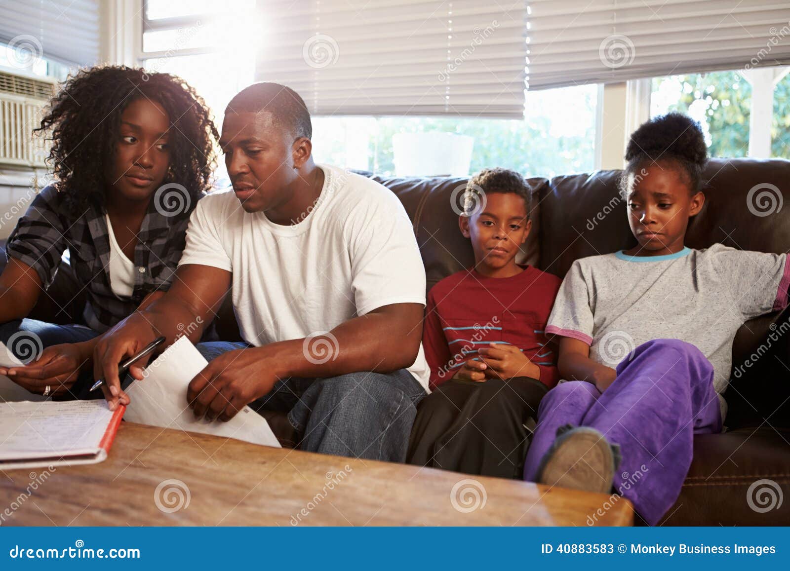 unhappy family sitting on sofa looking at bills