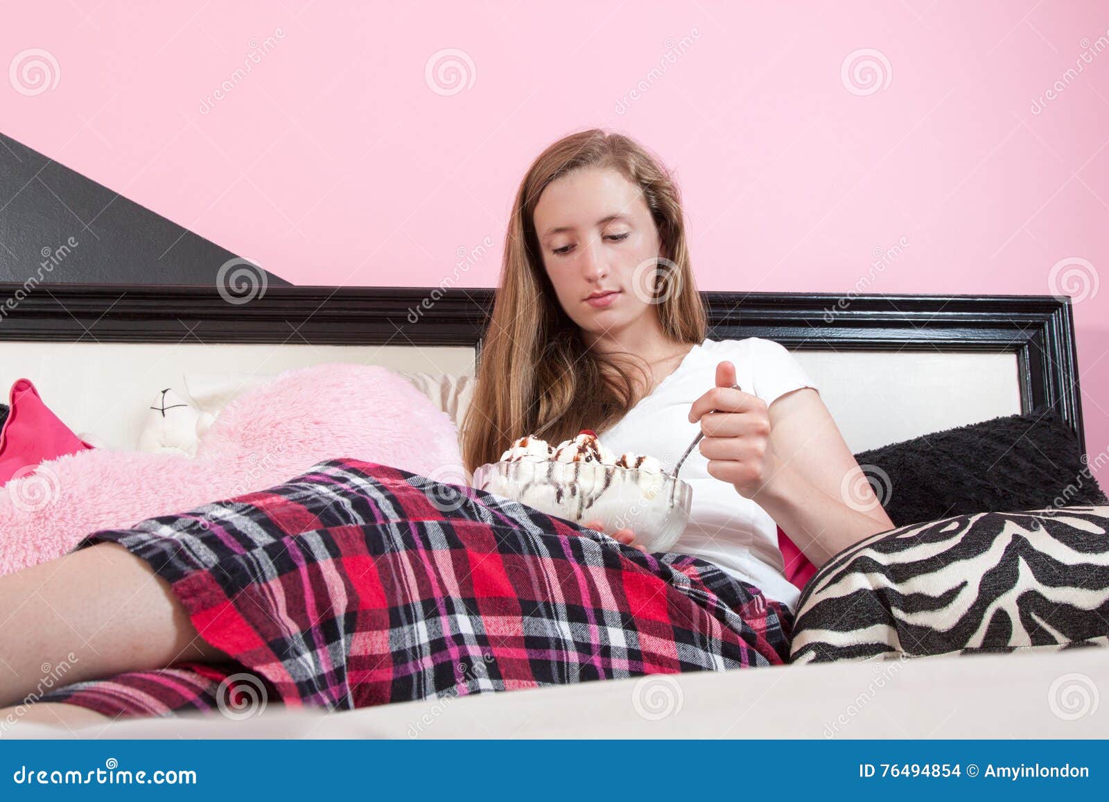 Unhappy Teen Eating Large Ice Cream Sundae In Her Room Stock