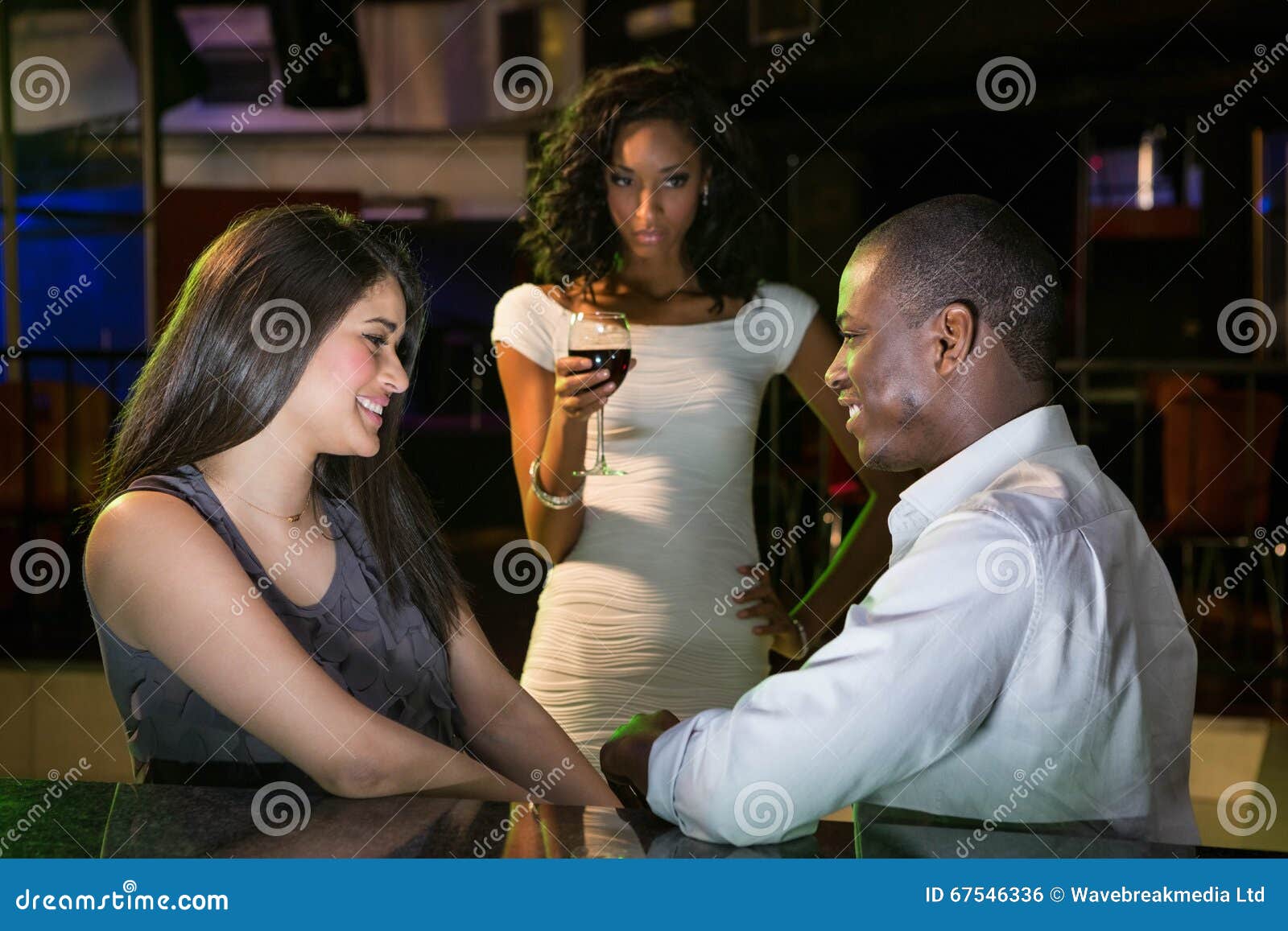 unhappy woman looking at a couple flirting near bar counter