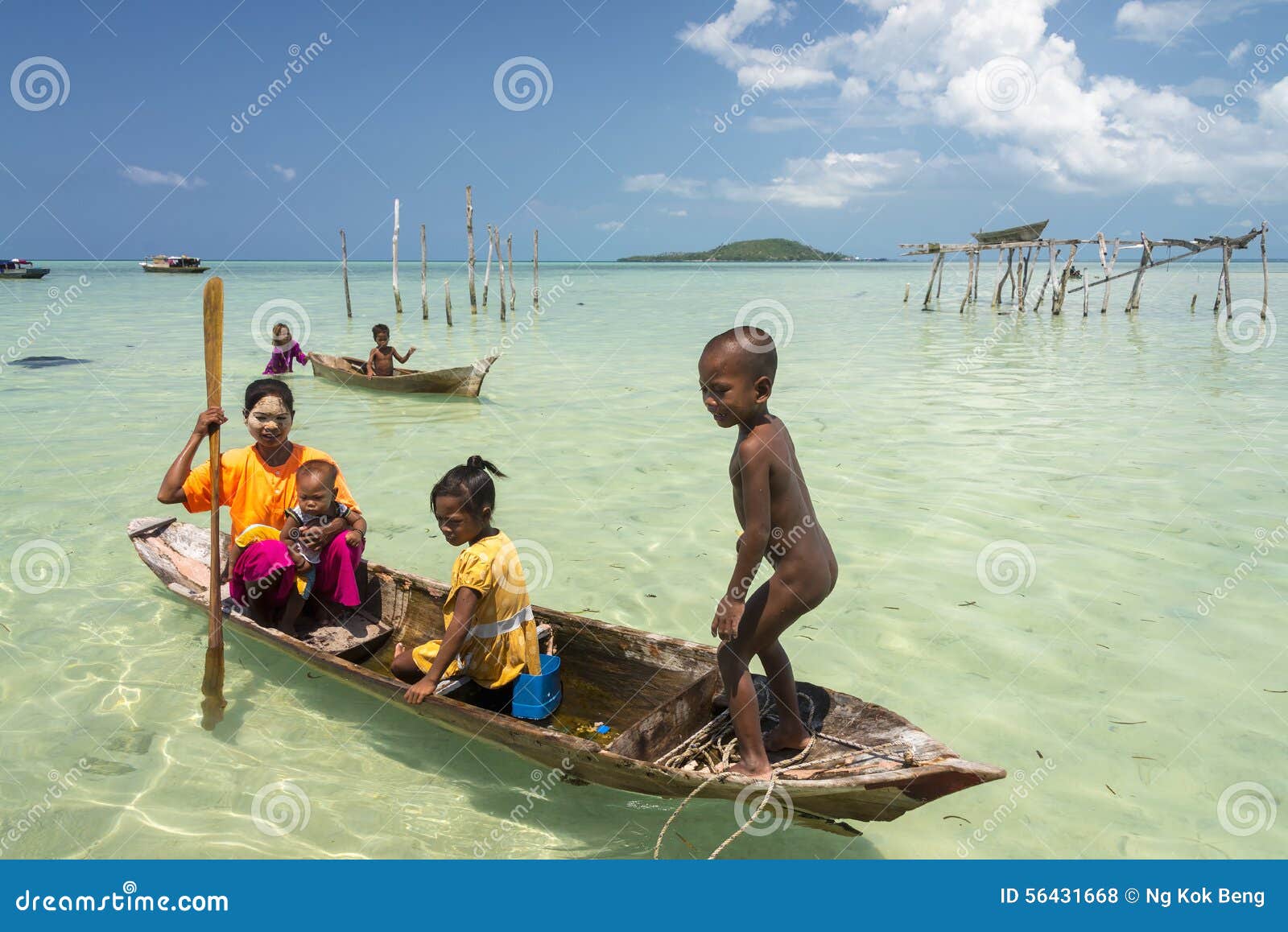 Unidentified Bajau Family Paddle A Dug Out Boat In Sunny 