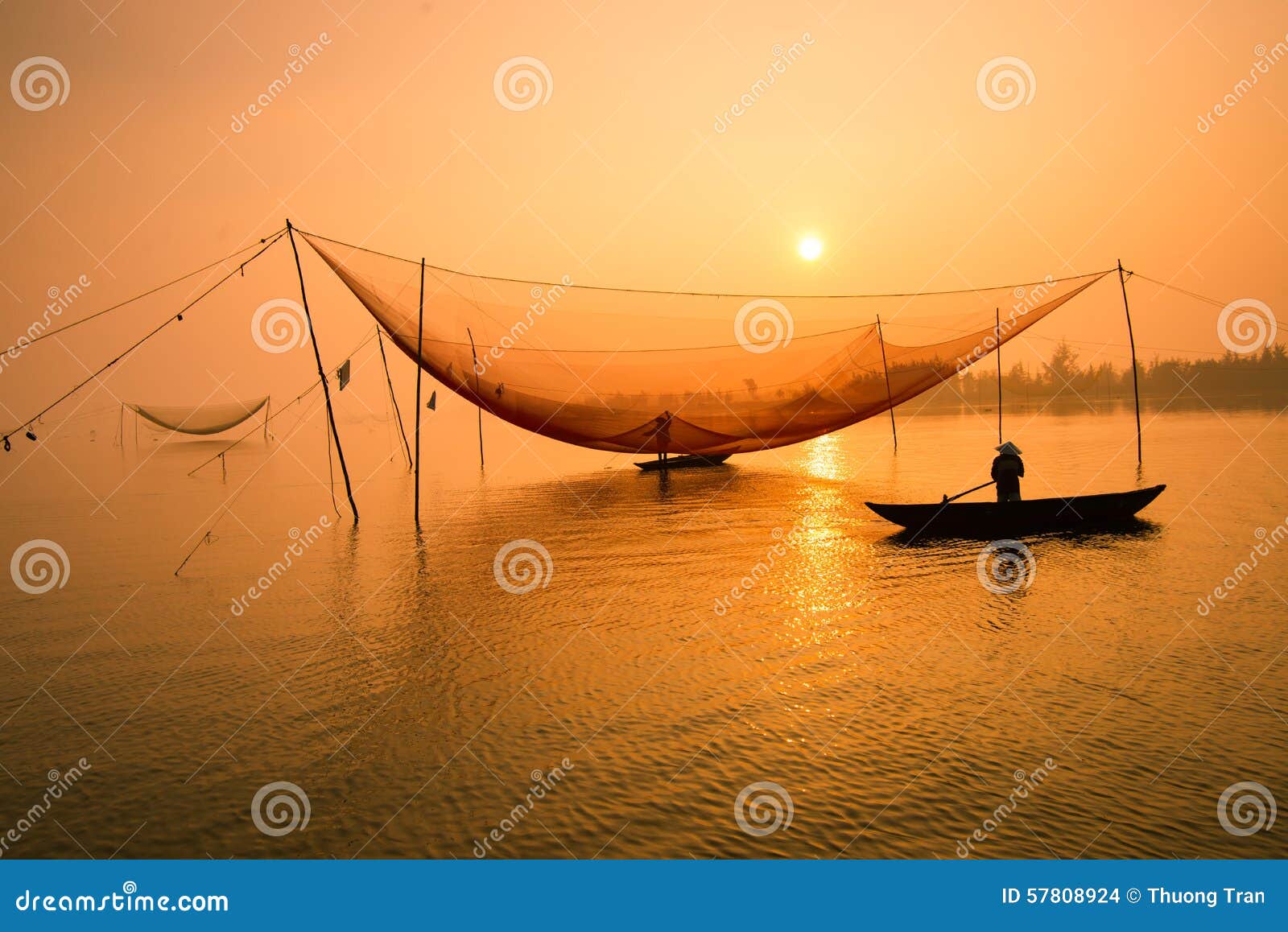 unidentified fisherman checks his nets in early morning on river in hoian, vietnam