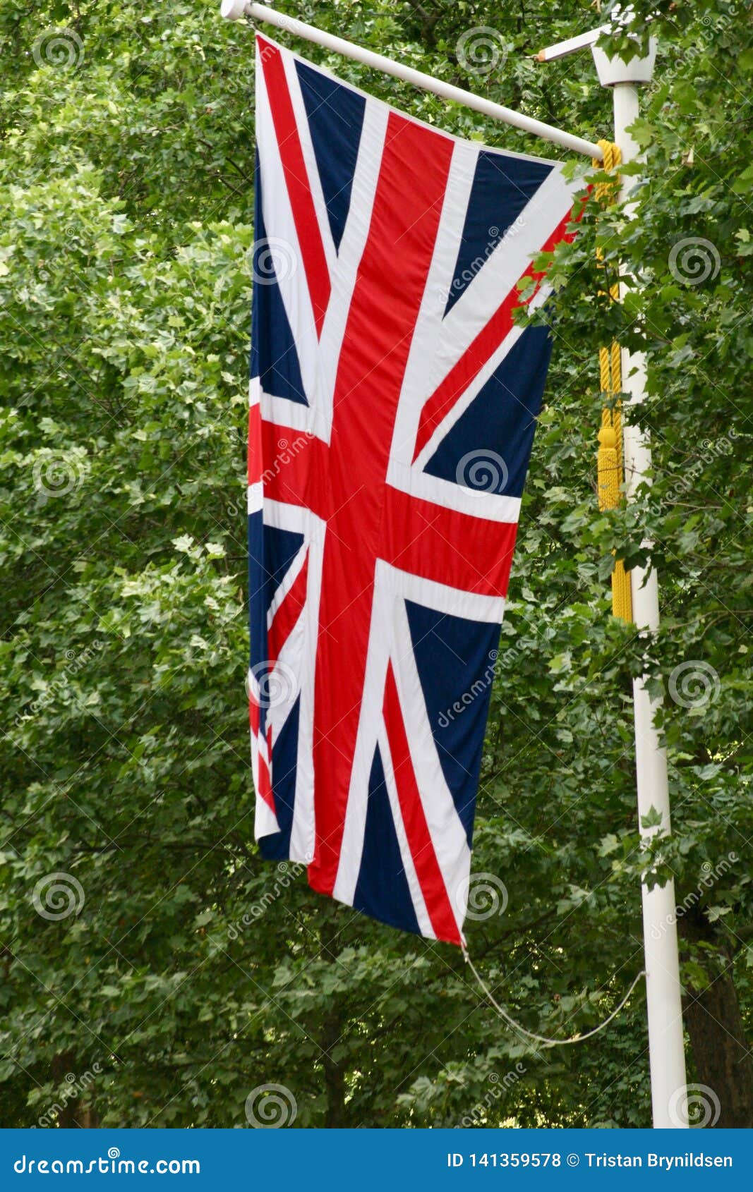 Union Jack Flag Flying Vertically With Trees In The Background Stock