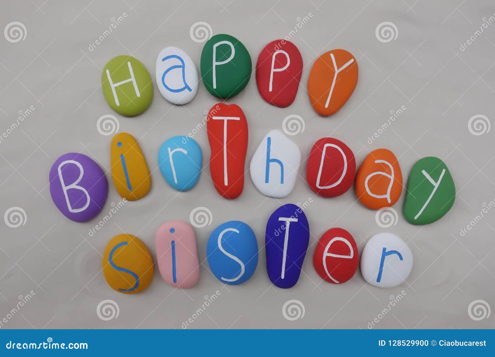 happy birthday sister with colored stones over white sand