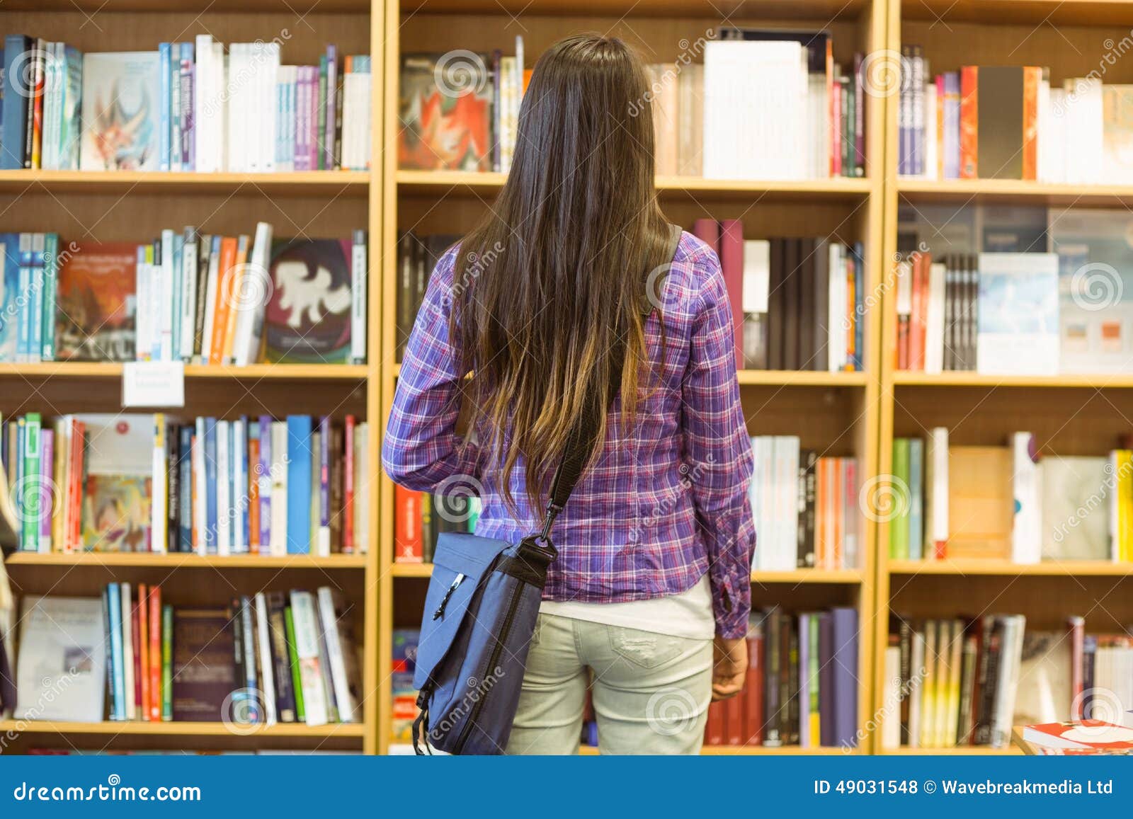 university student standing in the bookcase