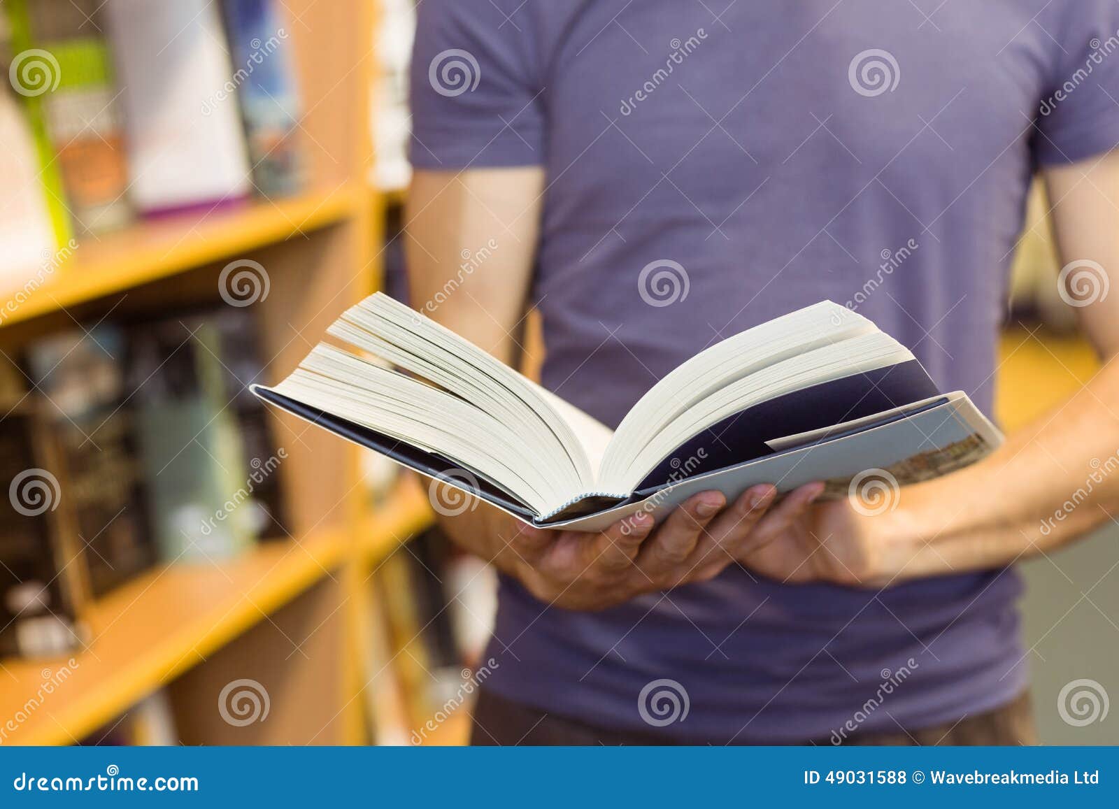 university student standing holding textbook