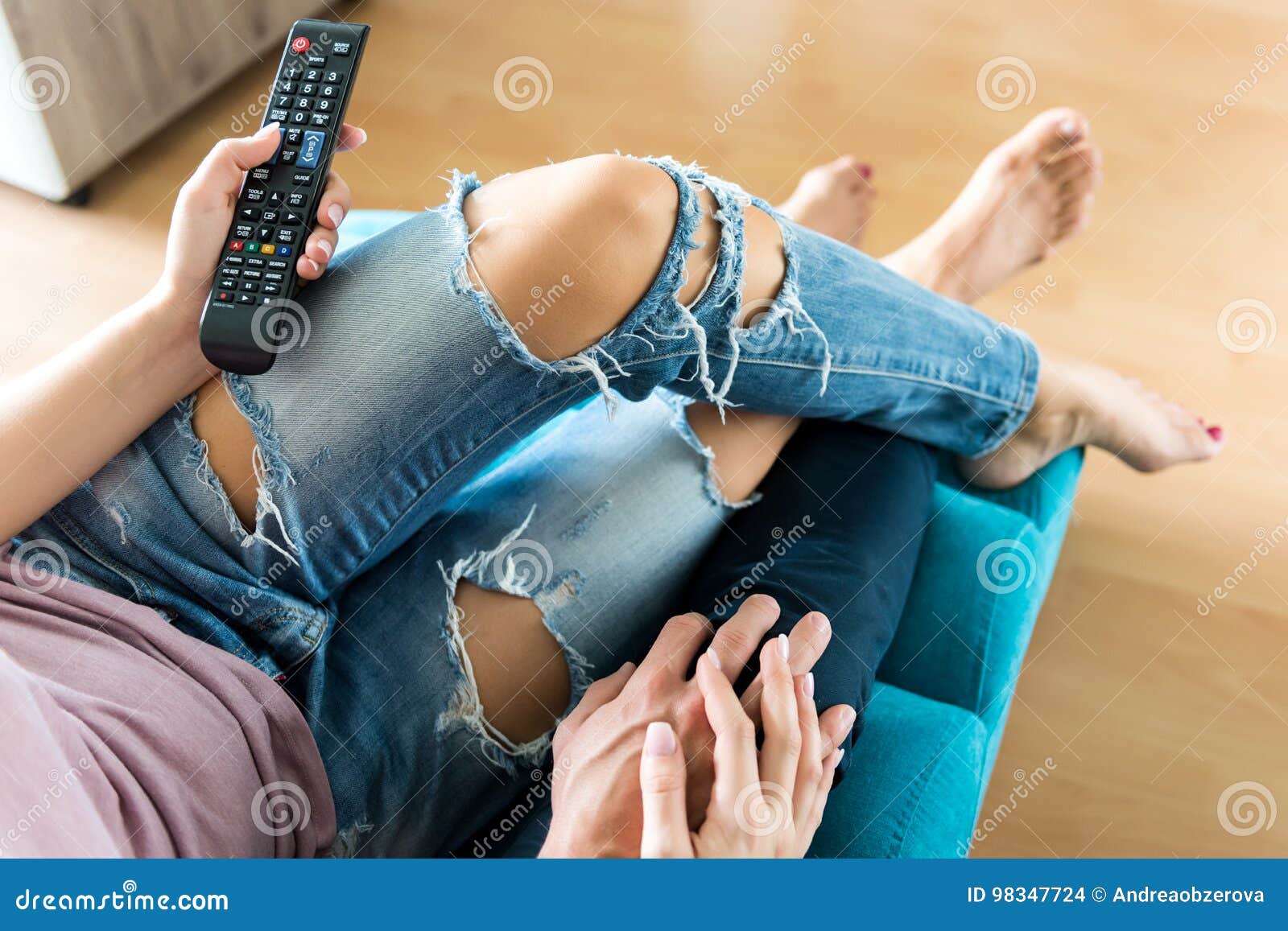 Unrecognisable Couple Watching Television At Their Modern Ho
