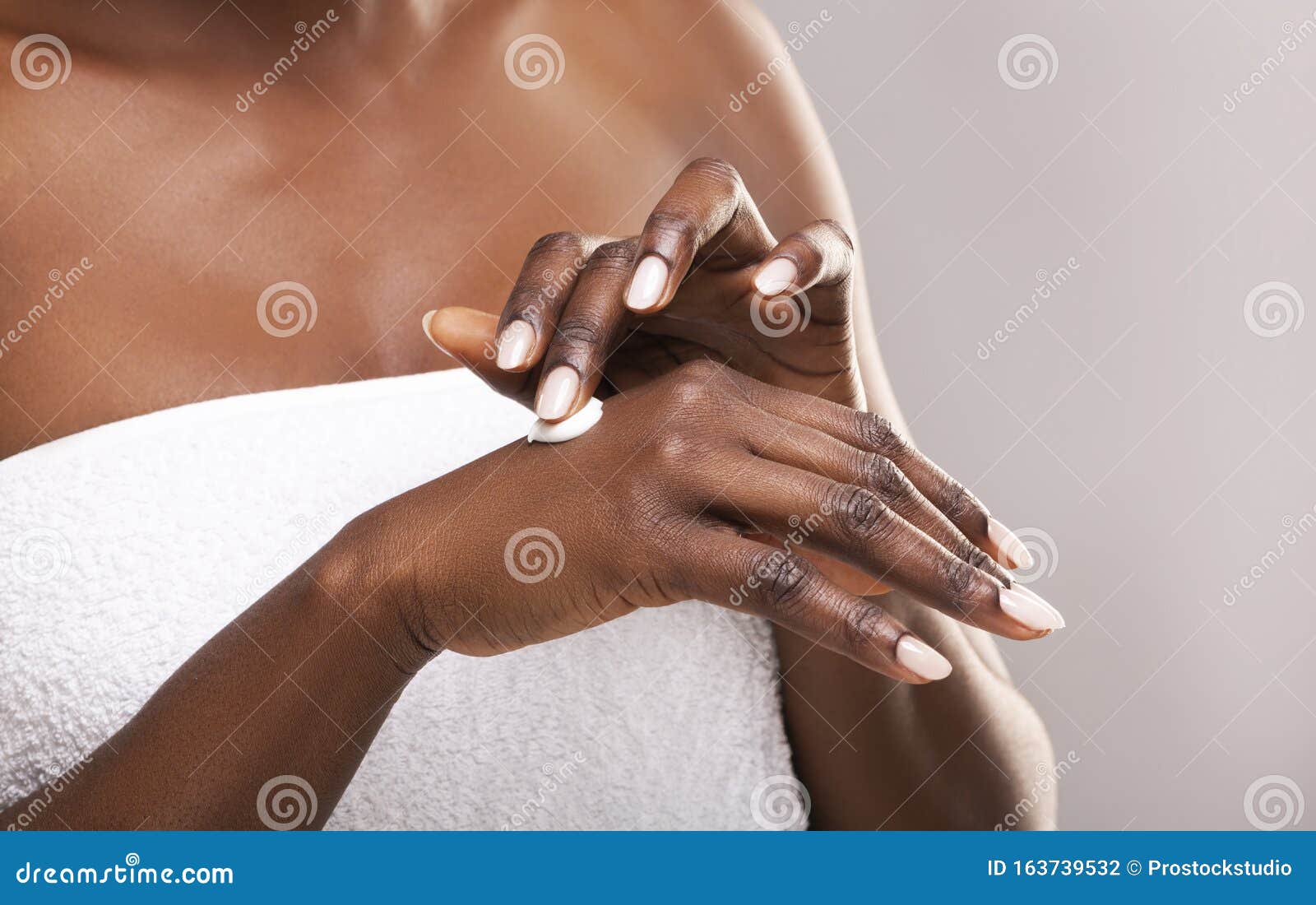 unrecognizable african american woman applying lotion to her hands, closeup