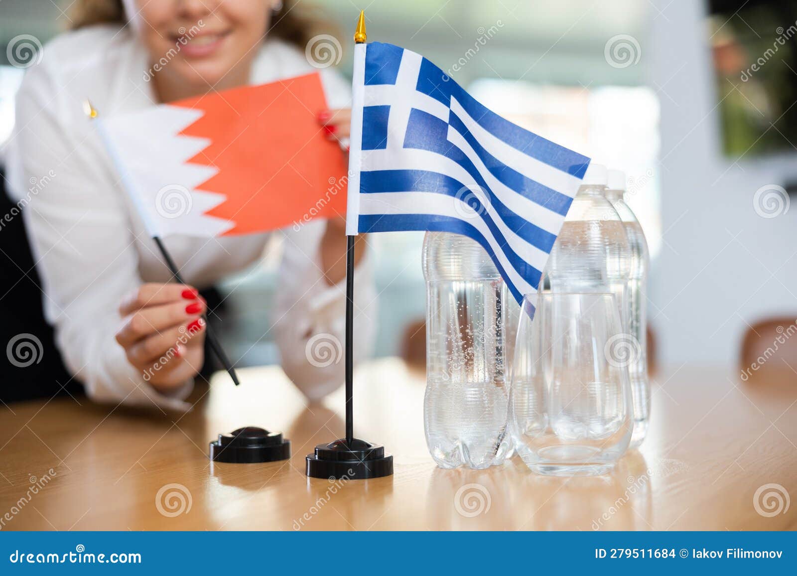 unrecognizable girl sets midget flags of greece and bahrein before international negotiations