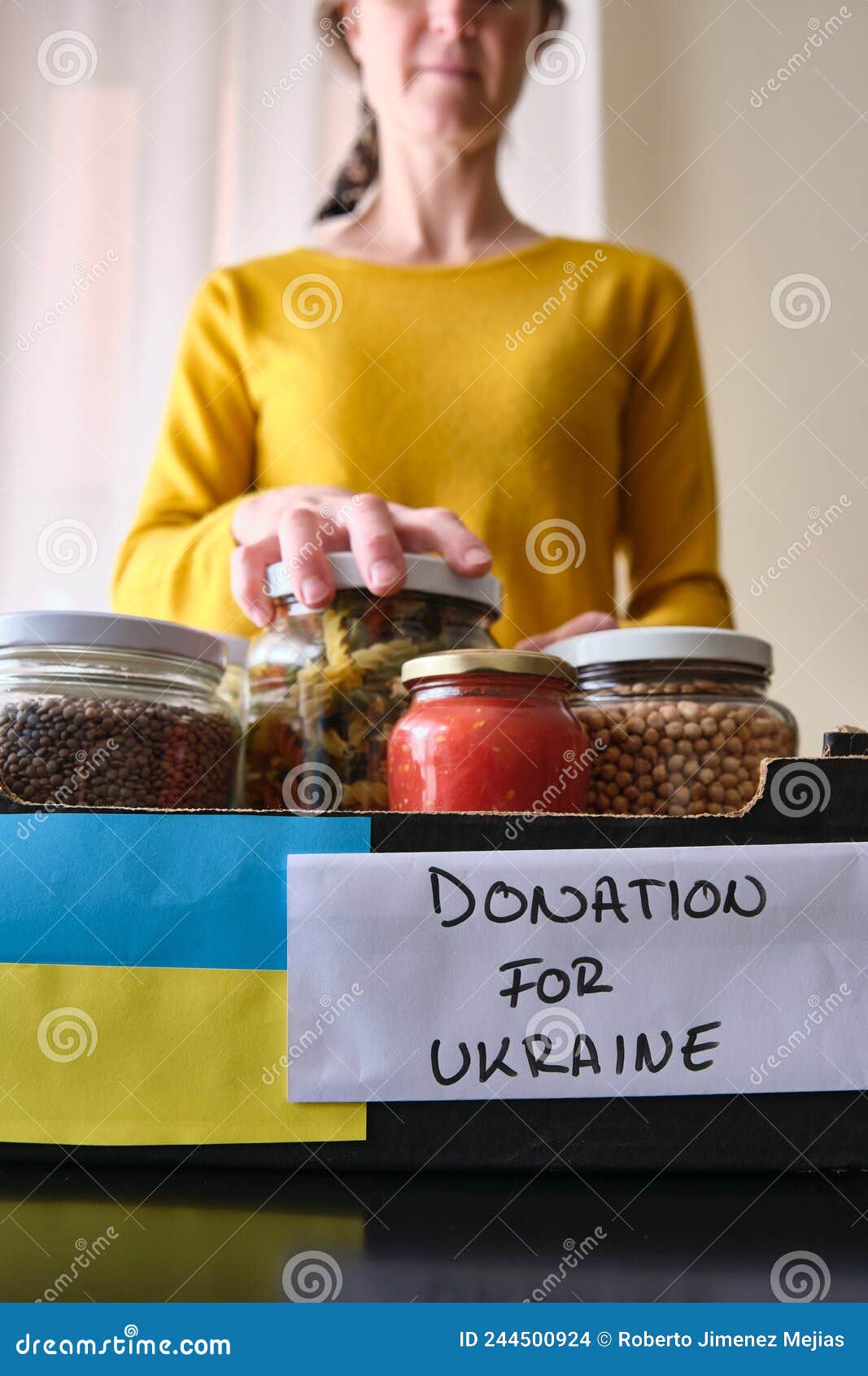 Unrecognizable Woman Putting Jars of Food in a Box To Donate To