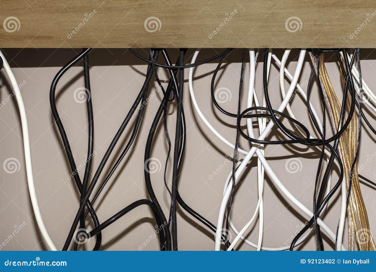 untidy cables hanging behind a computer desk