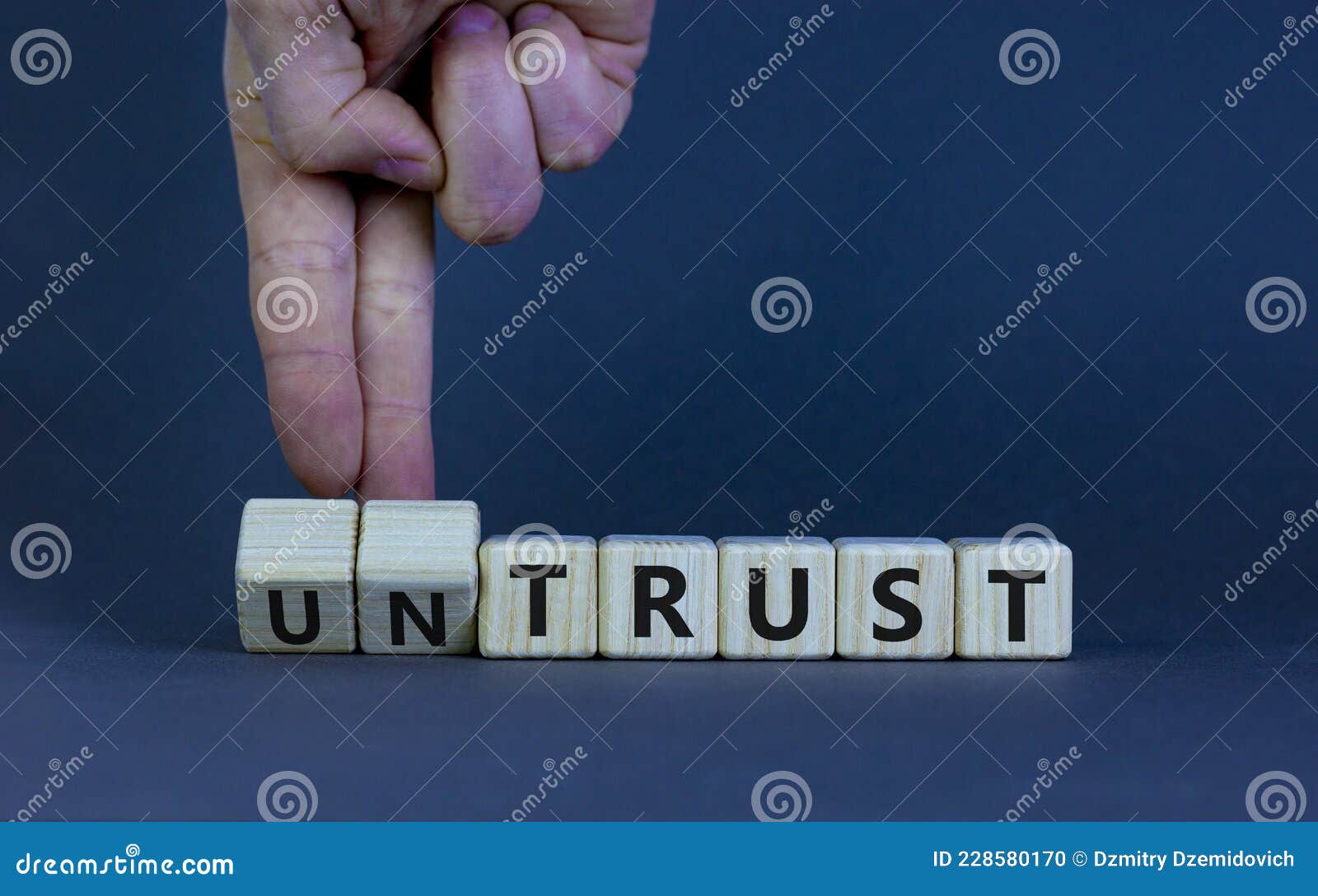 untrust or trust . businessman turns wooden cubes, changes words `untrust` to `trust`. beautiful grey table, grey backgr