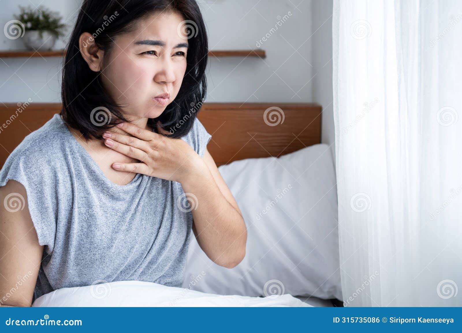 asian woman suffering from nausea in bed. food poisoning or pregnancy concept