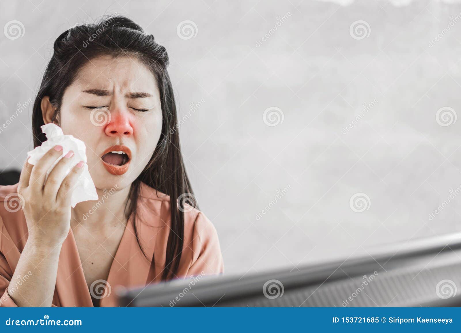 unwell female asian having flu and cold sneezing at work place