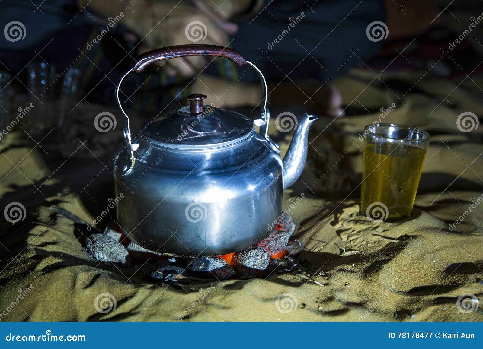 Uomo in attrezzatura tradizionale del Tuareg che produce tè in un deserto alla notte