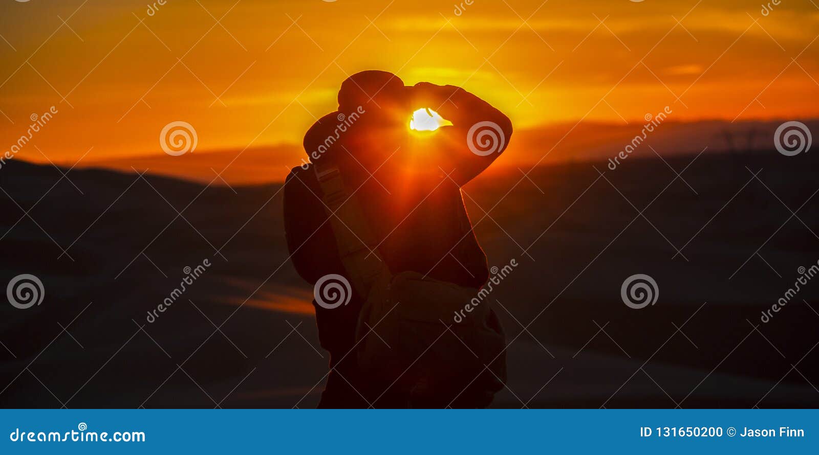 Uomo che prende un'immagine delle dune di sabbia e di tramonto Siluetta di un uomo con la macchina fotografica in California al tramonto L'uomo sta prendendo un'immagine delle dune di sabbia e la regolazione del sole nell'orizzonte dorato