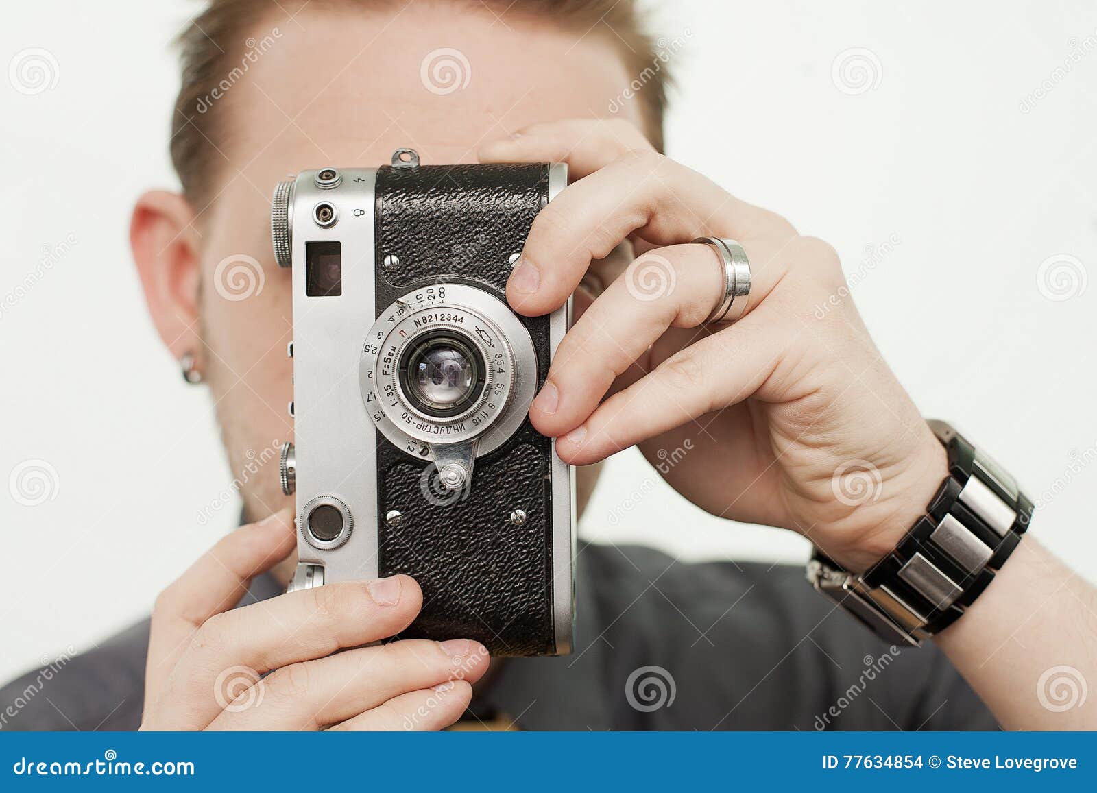 Uomo con la macchina fotografica d'annata. Giovane maschio facendo uso di una macchina da presa d'annata di 35mm