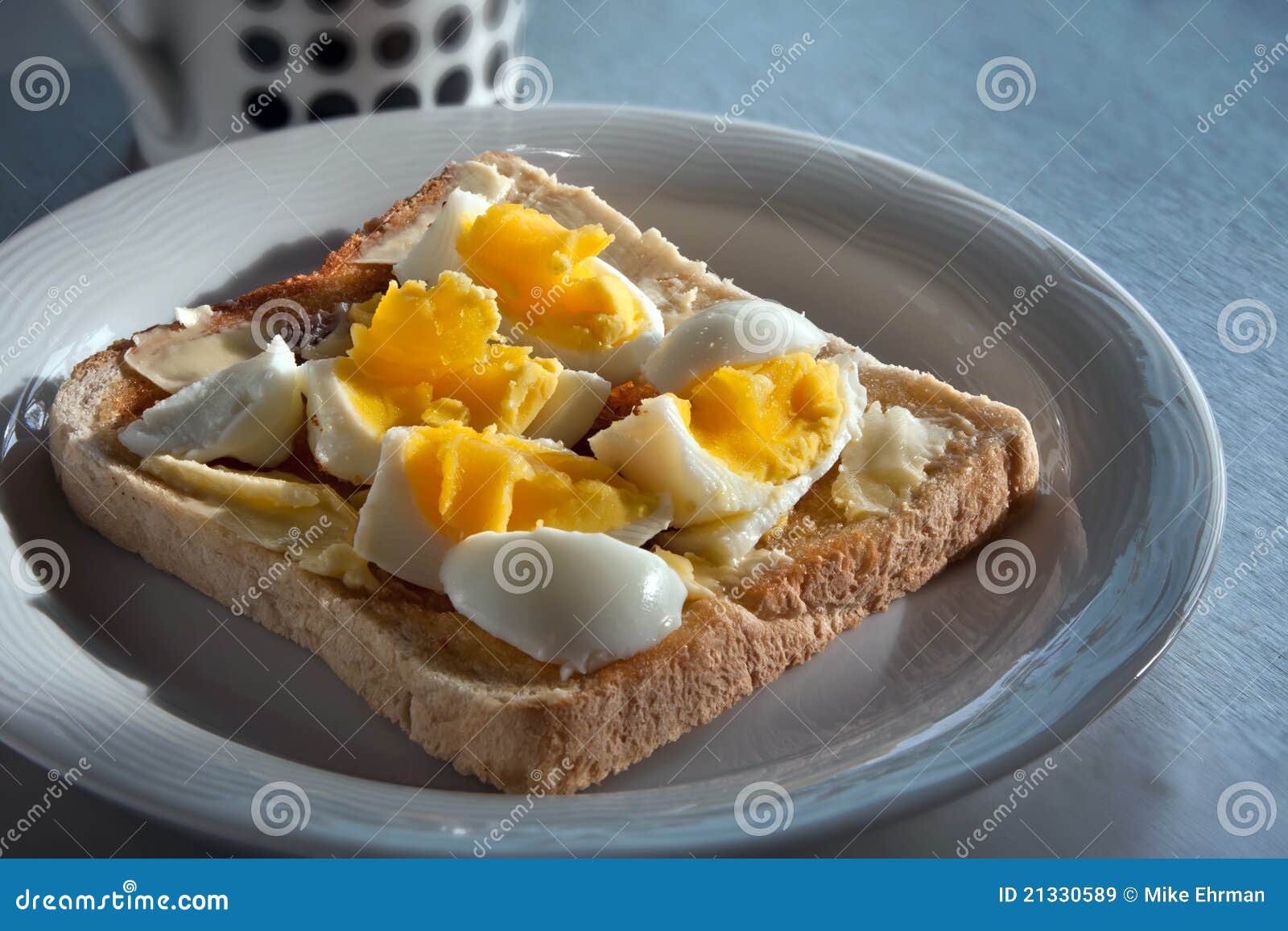 Il pasto sano della prima colazione di mattina ha bollito l'uovo su pane tostato con burro