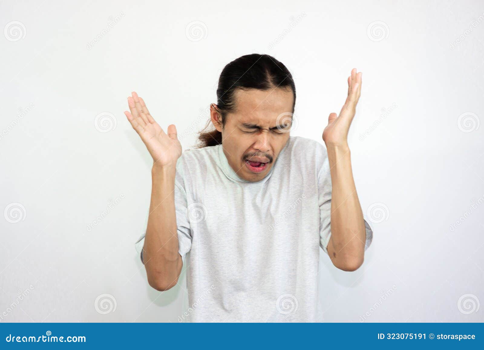 upset and angry man raising both hands while shouting. looking at the camera angrily. in white background