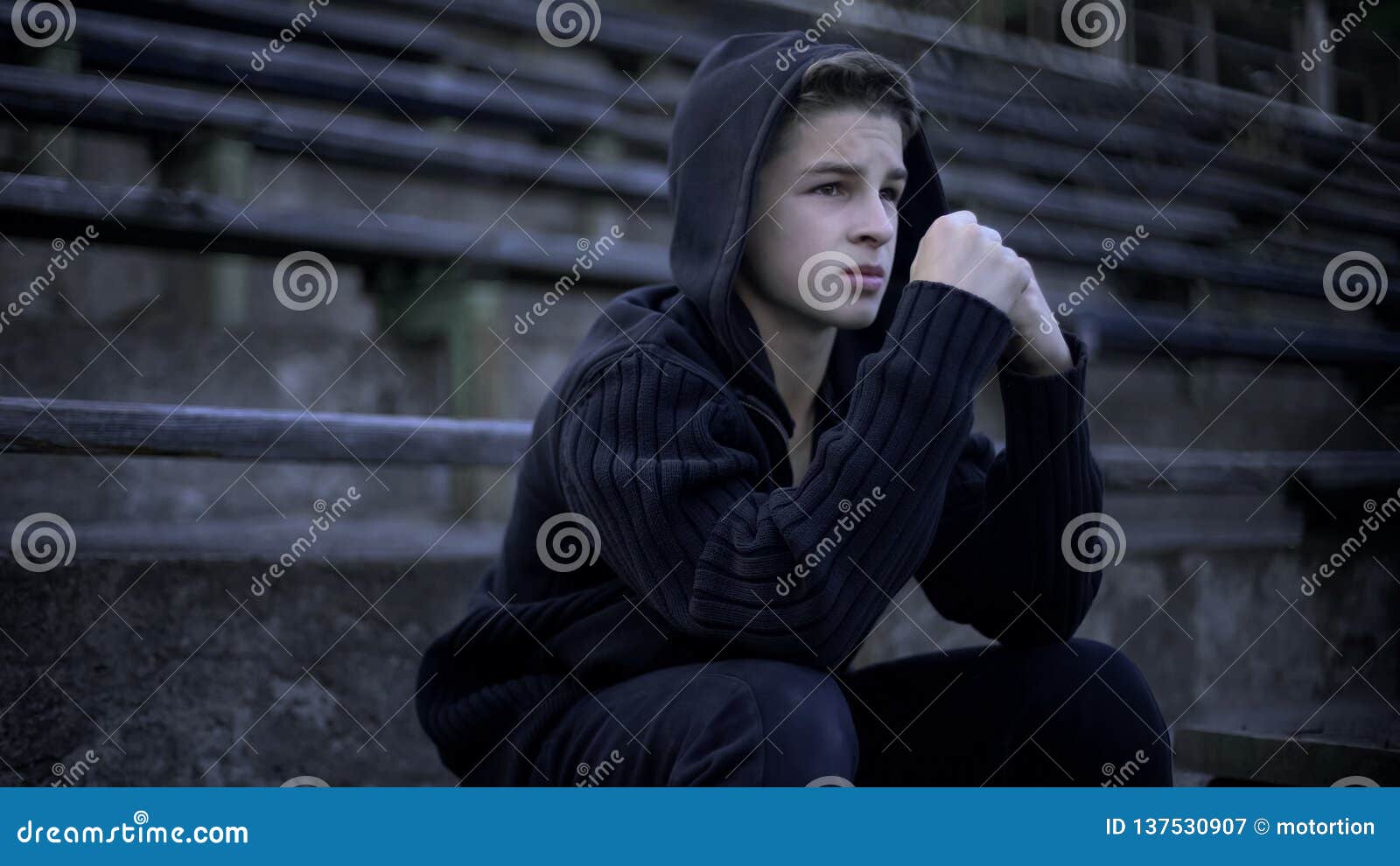upset boy feels depression, sitting on stadium tribune, loneliness and sorrow