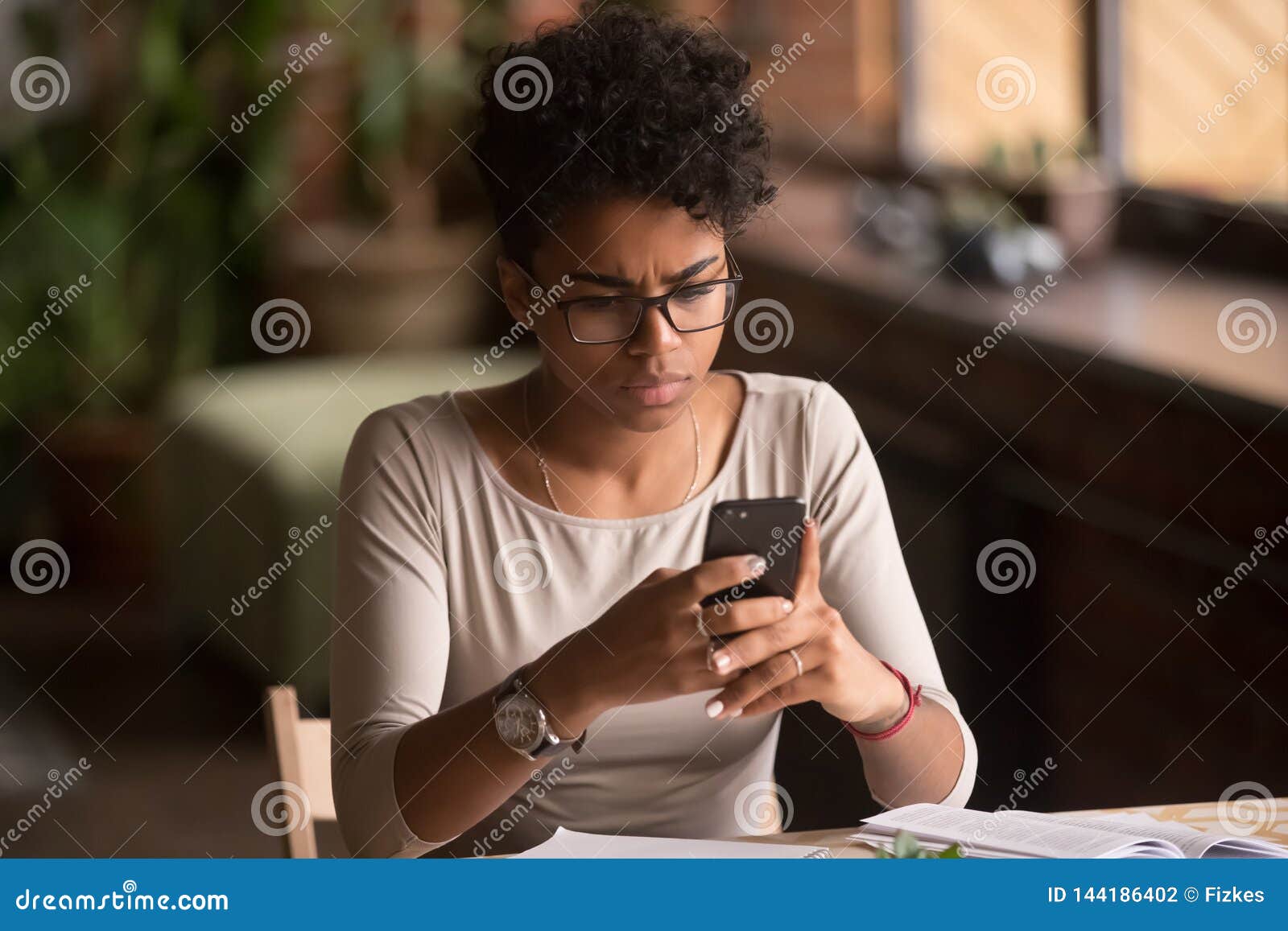 upset confused african woman holding cellphone having problem with phone