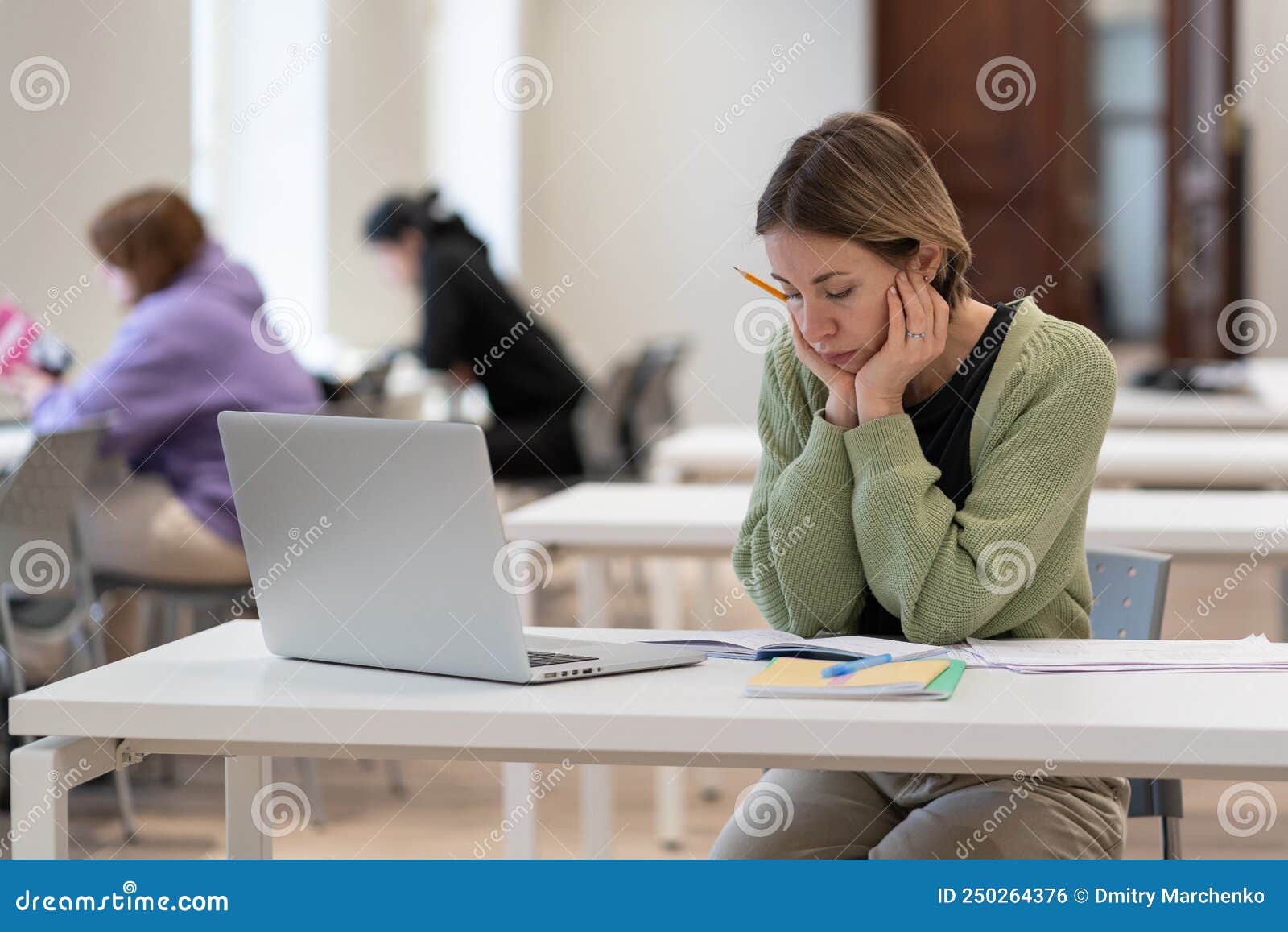 upset female mature-age student working on difficult homework in library, tired of studying
