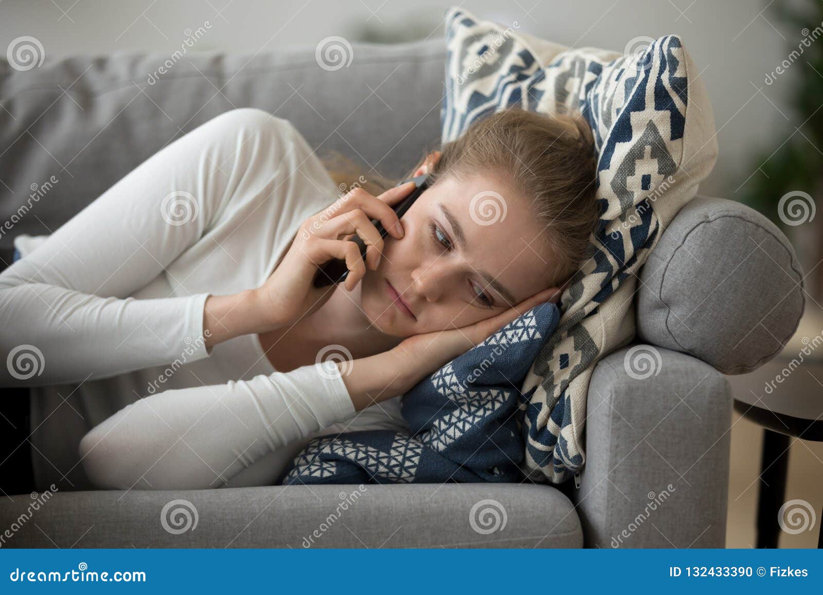 upset girl lying on couch having unpleasant phone talk