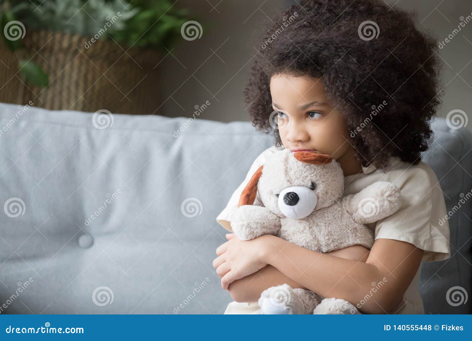 upset lonely african kid girl holding teddy bear looking away