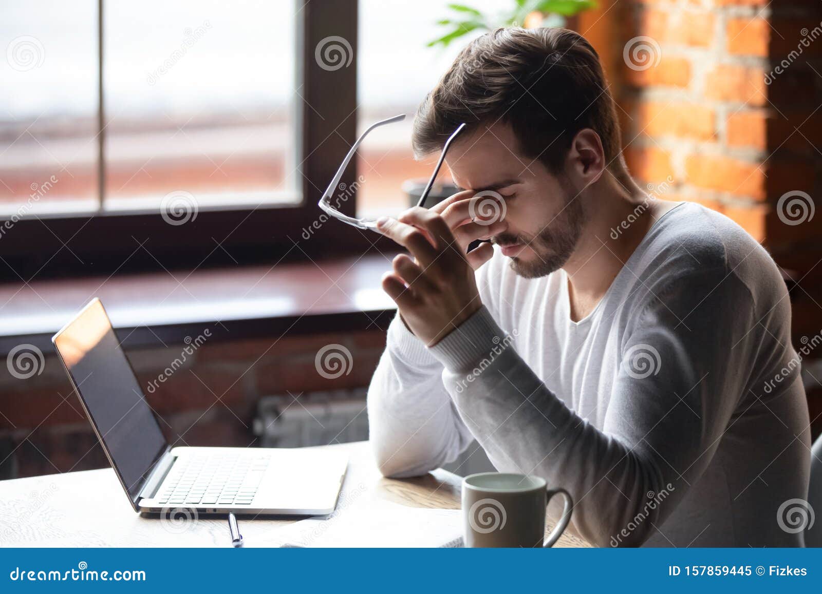 upset man massaging nose bridge, taking off glasses, feeling eye strain