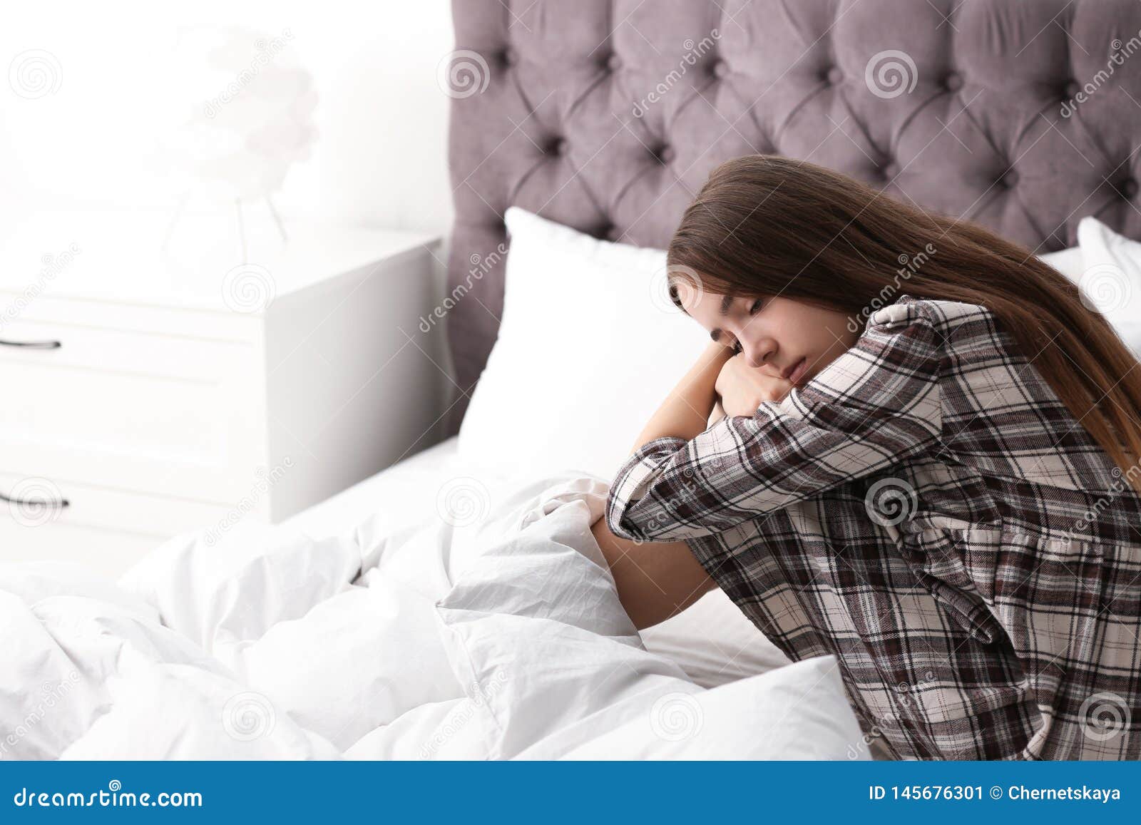 Photo about Upset teenage girl sitting on bed. 