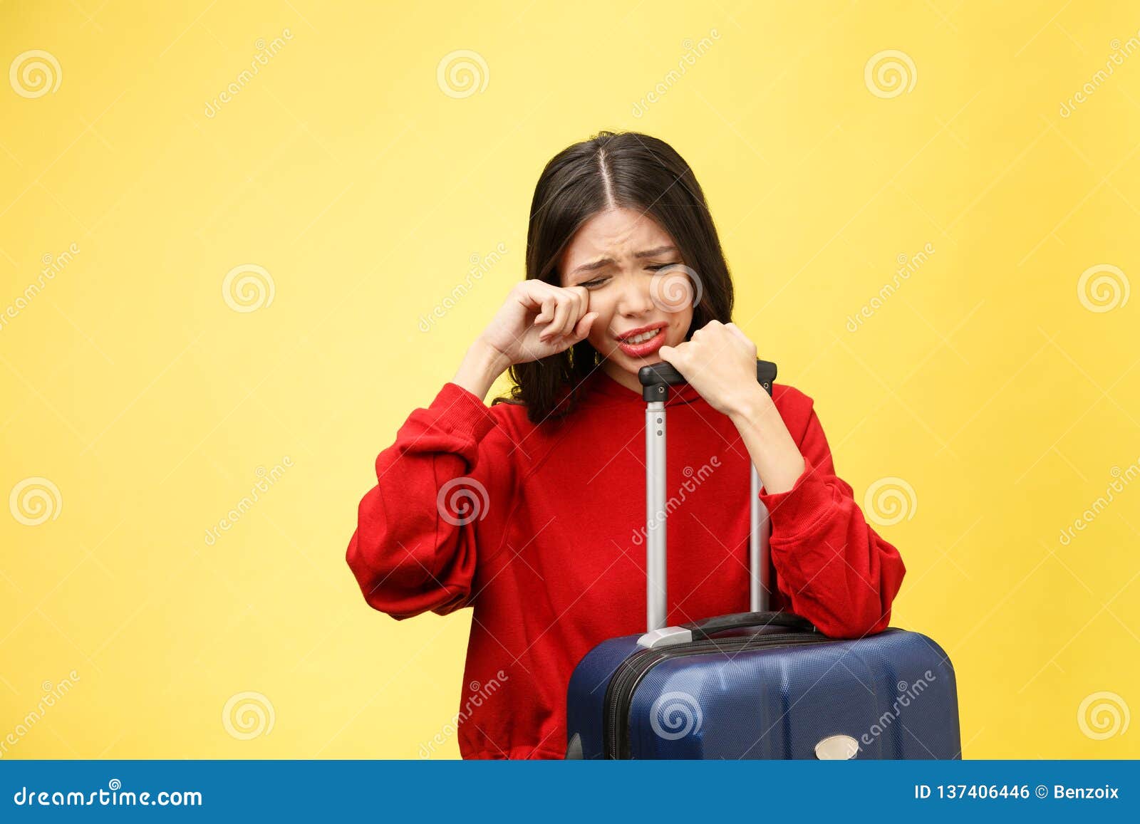 upset tourist woman in summer casual clothes sit on suitcase put hands on head on yellow orange background