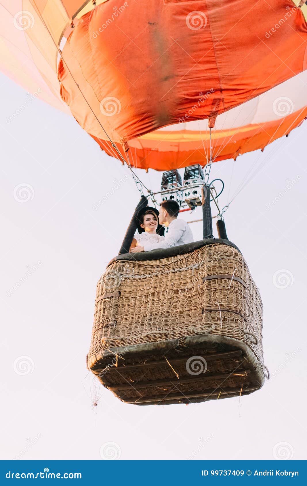 the upside view of the airballoon flying with the smiling vintage dressed newlyweds.