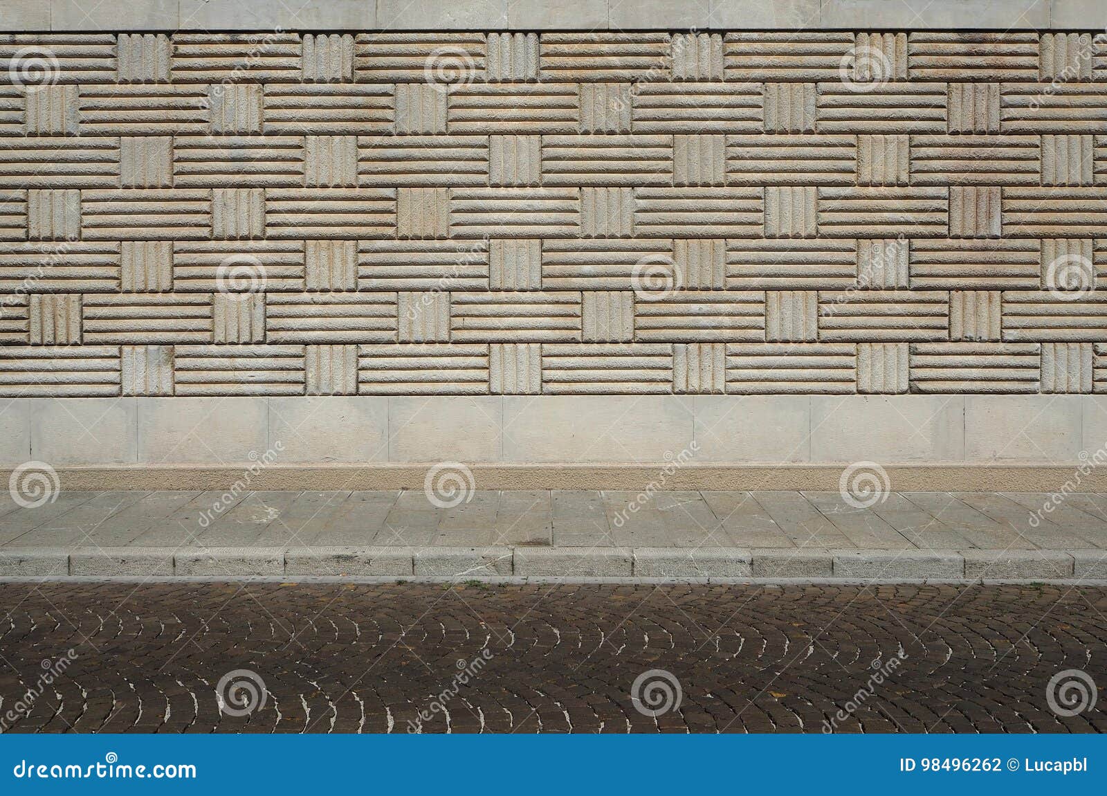 urban background. wall with geometric patterns, sidewalk and street with porphyry cubes