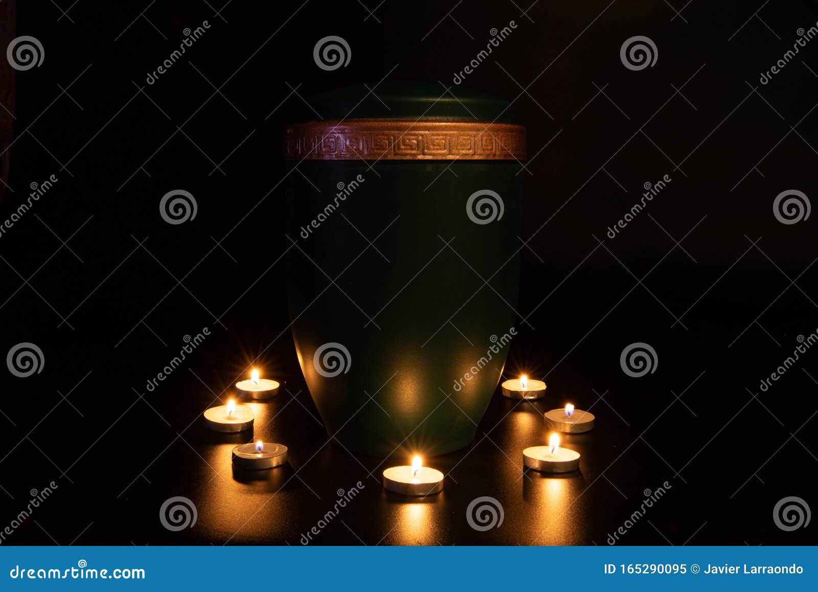 green urna with golden edge surrounded with small burning candles
