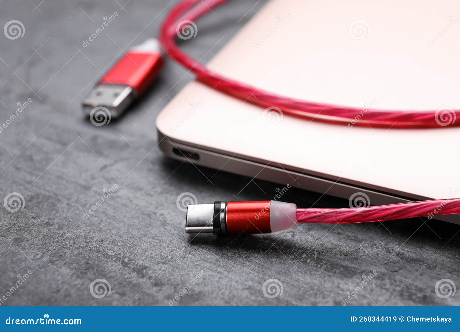 USB Cable with Type C Connector and Laptop on Grey Table, Closeup Stock