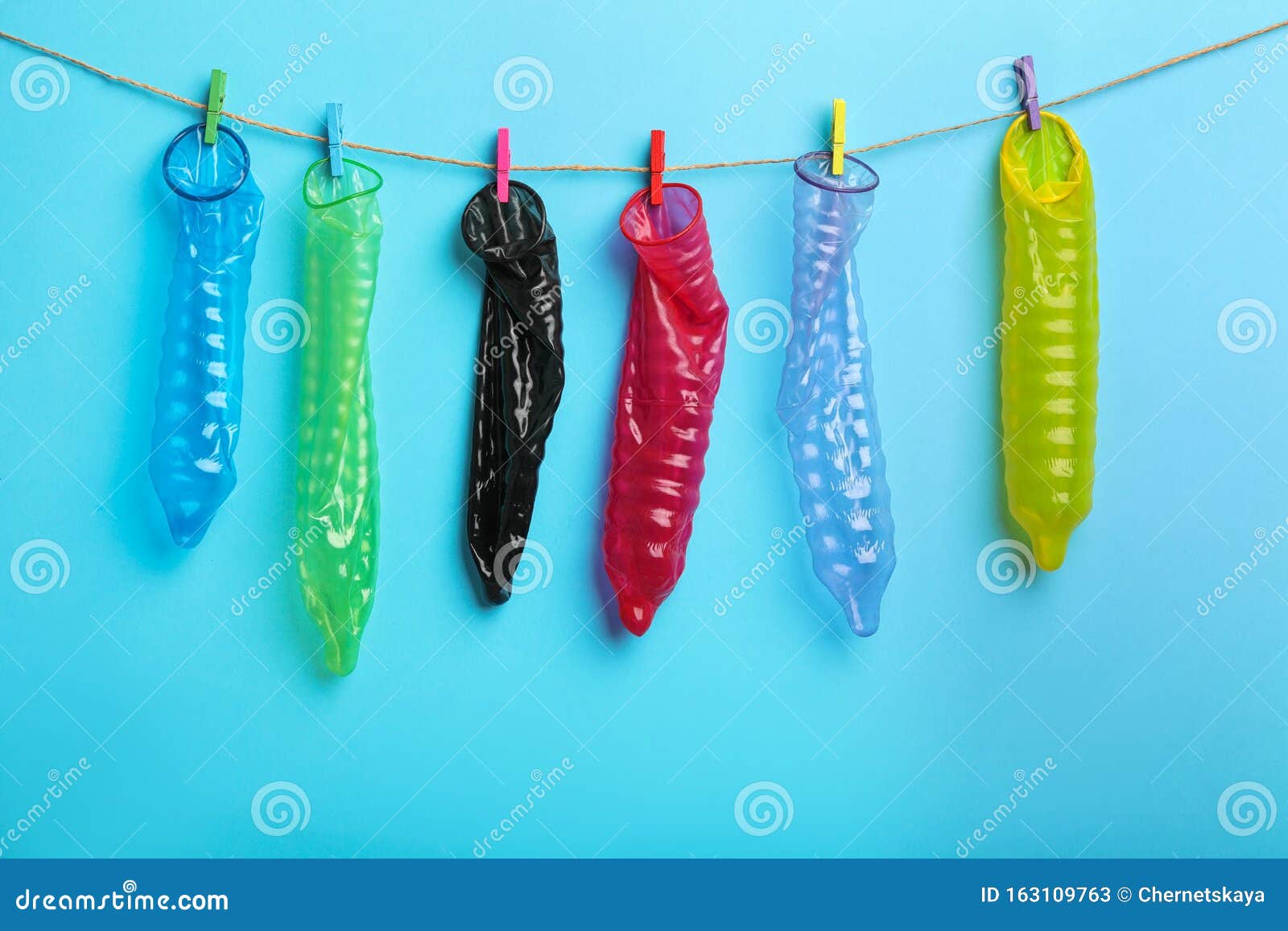 Used Colorful Condoms Hanging On Clothesline Against Blue Background Safe Sex Concept Stock