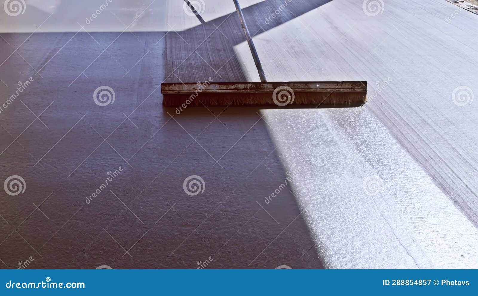 Using a Broom, a Construction Worker Brushes Fresh, Wet Concrete Which