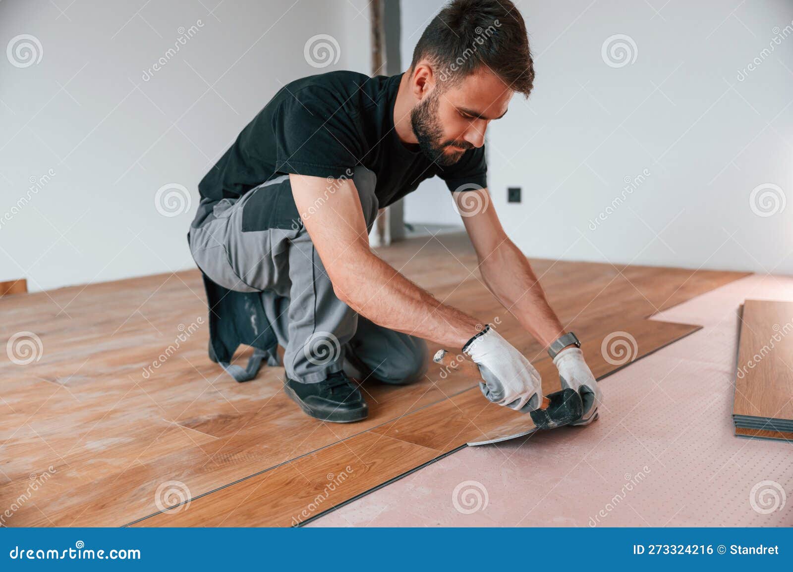 Using the Rubber Hammer. Man is Installing New Laminated Wooden Floor