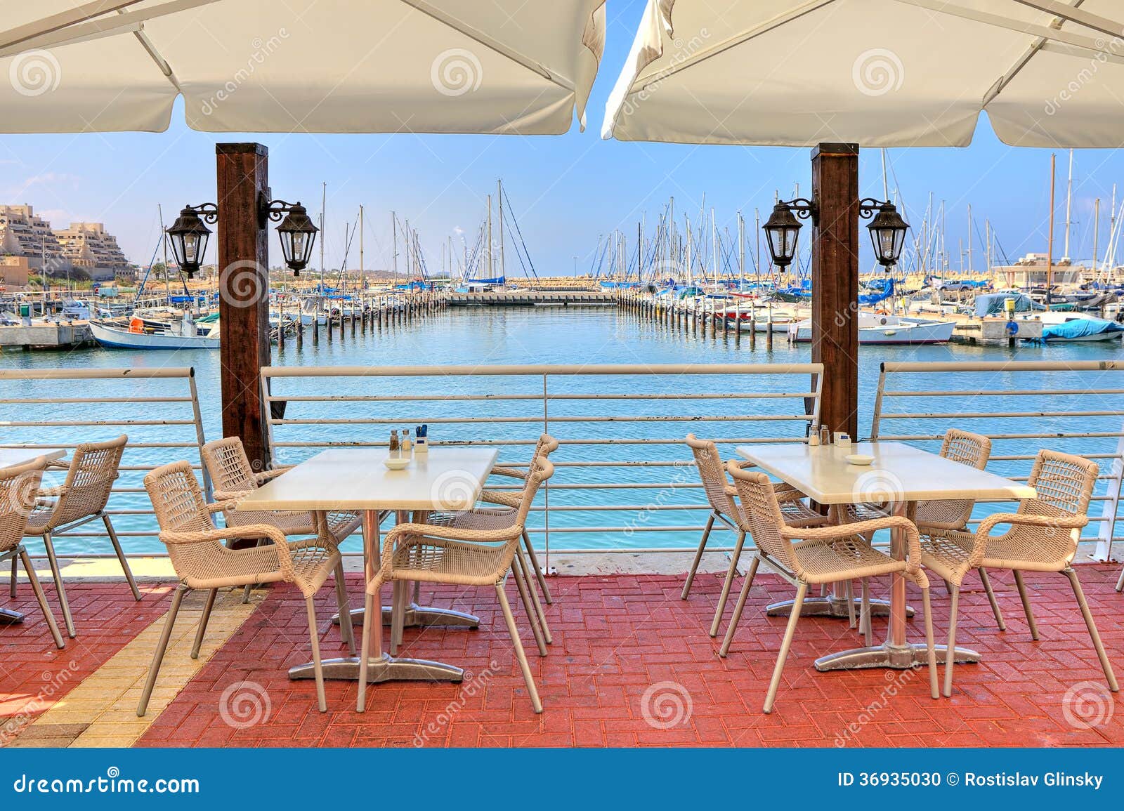 Utomhus- restaurang på medelhavet. Vittabeller och stolar av den utomhus- restaurangen på promenad längs marina på medelhavet i Ashkelon, Israel.