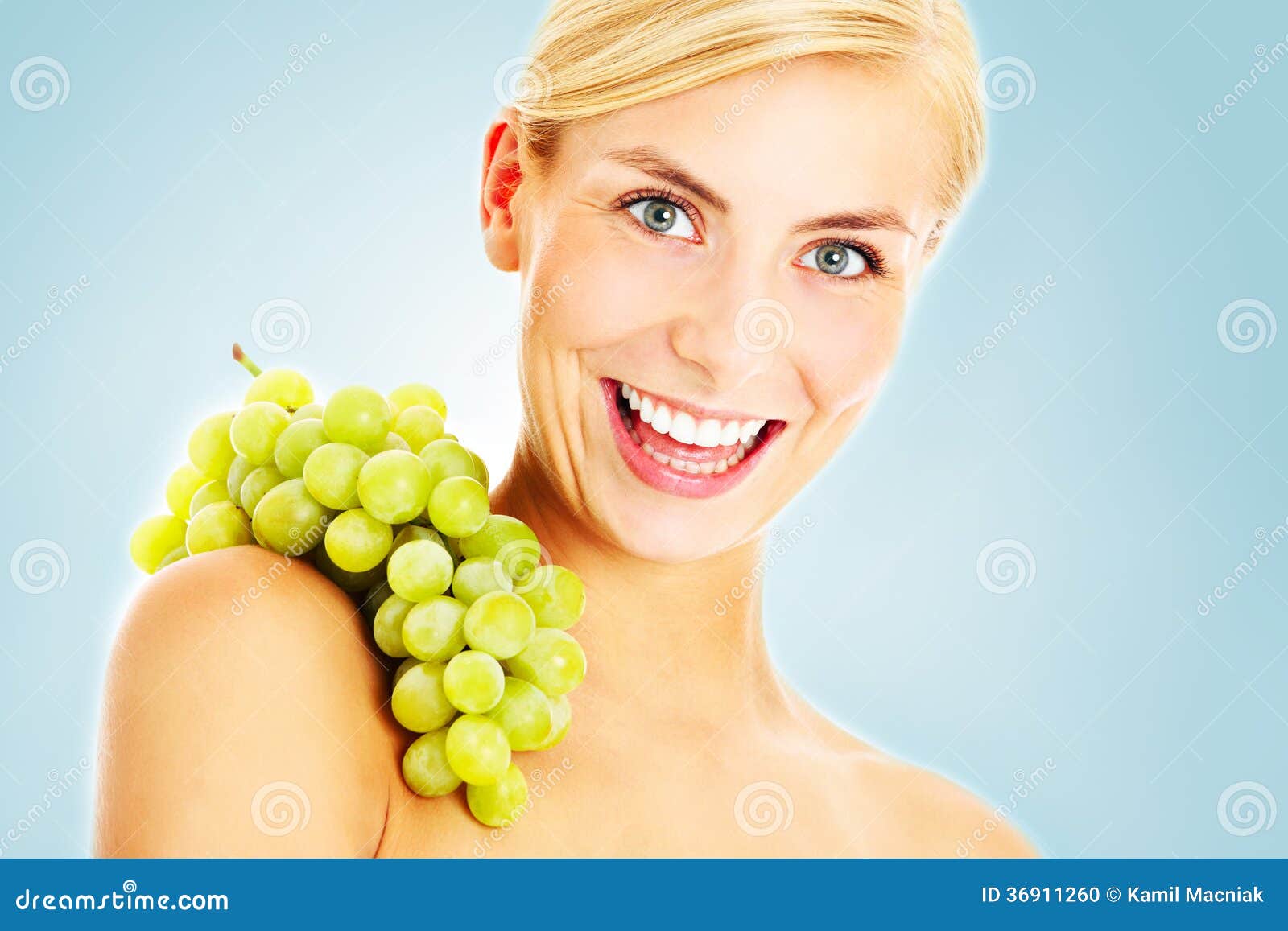 Uva energetica. Un'immagine di bella giovane donna che posa con l'uva sopra fondo blu